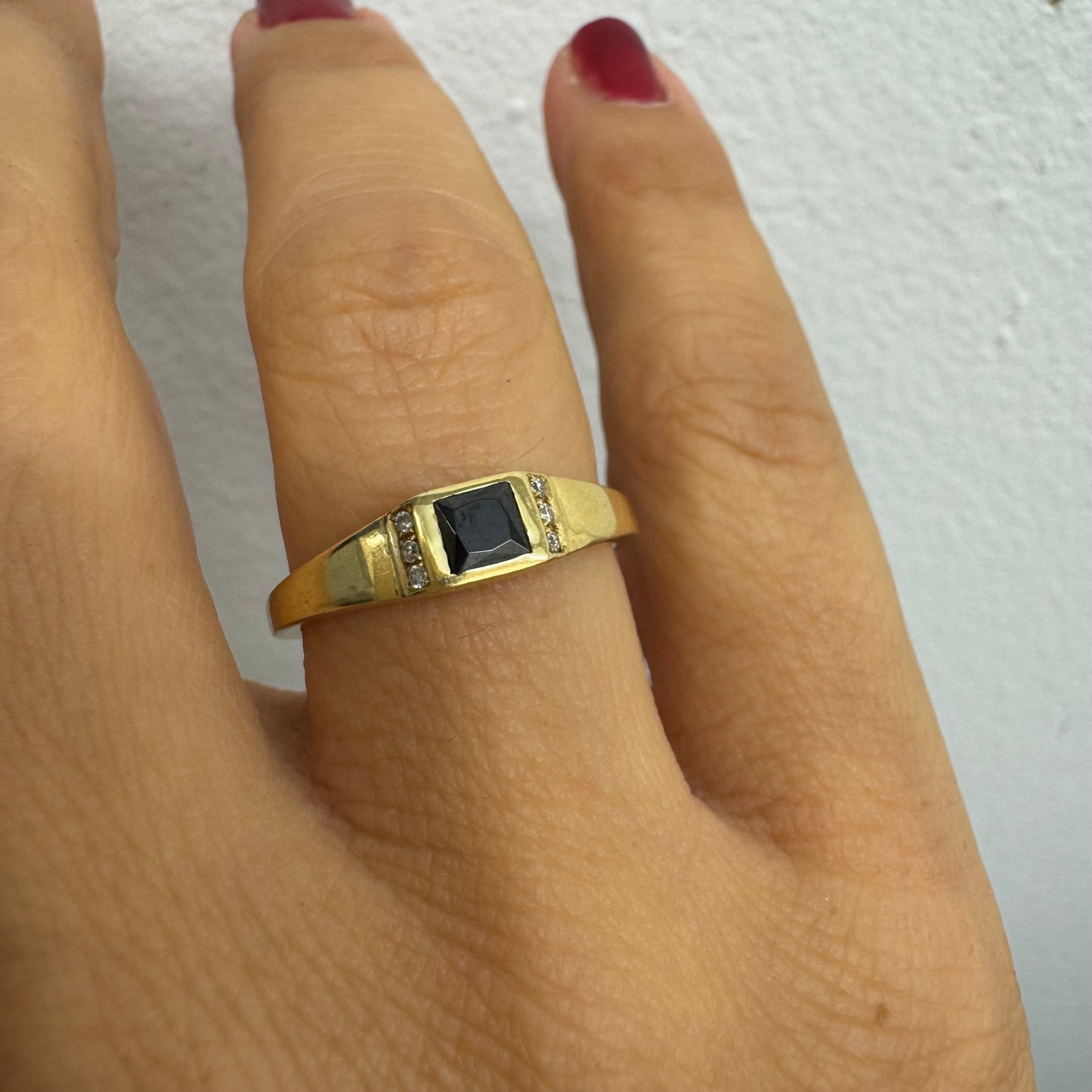 טבעת זהב 14 קראט משובצת אבן ספינל שחור בחיתוך ריבועי במרכז ויהלומים קטנים משני הצדדים.