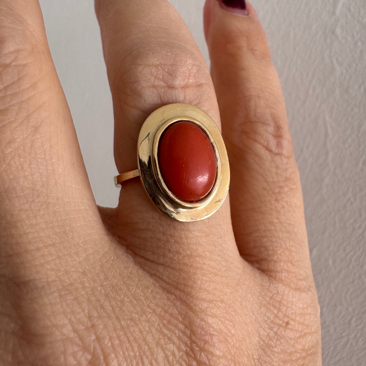 טבעת זהב 18 קראט משובצת אבן קורל אובלית בגימור קבושון, משובצת במסגרת חלקה ונקייה.