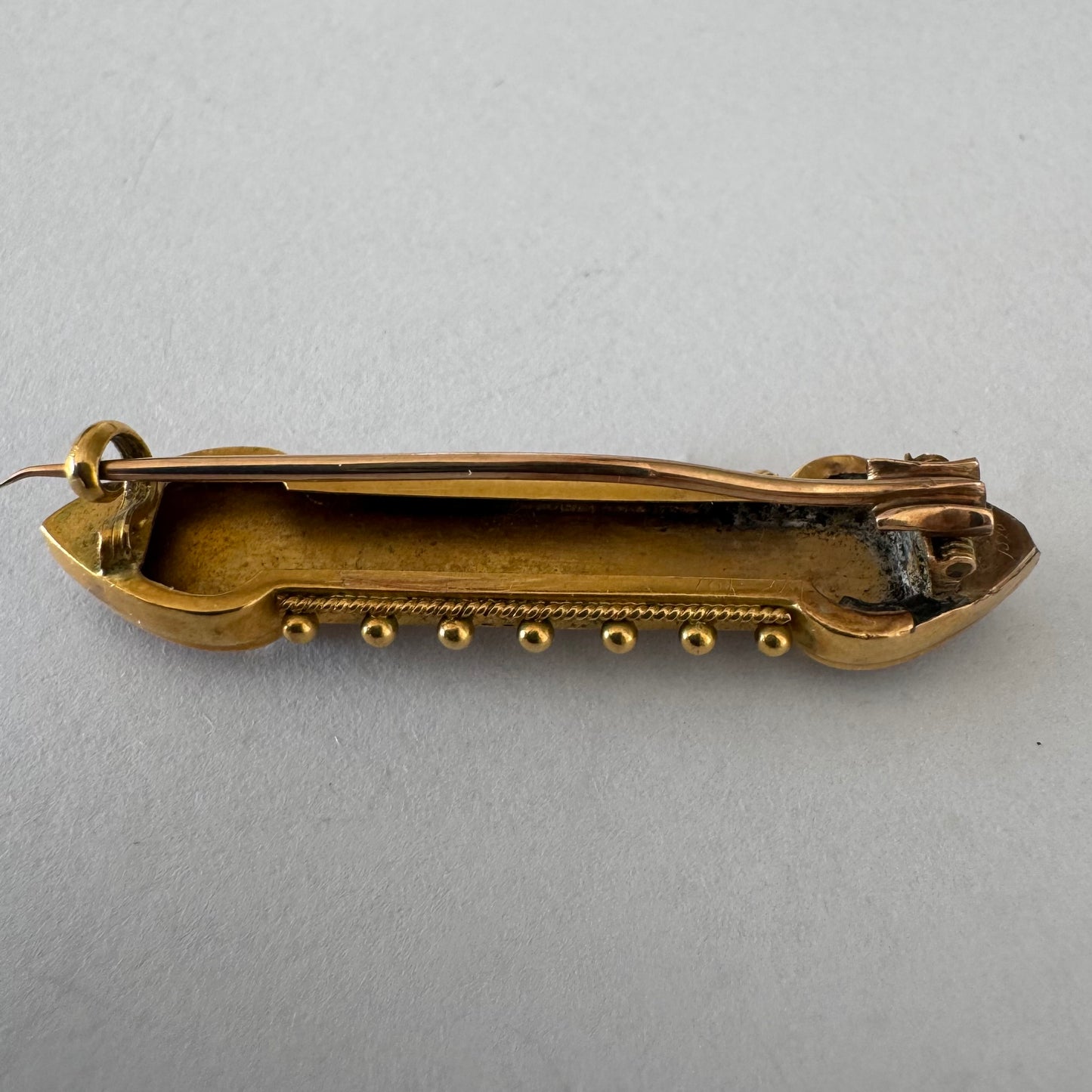 14K gold brooch featuring an ornate geometric design with intricate gold detailing & symmetrical decorative motifs.
