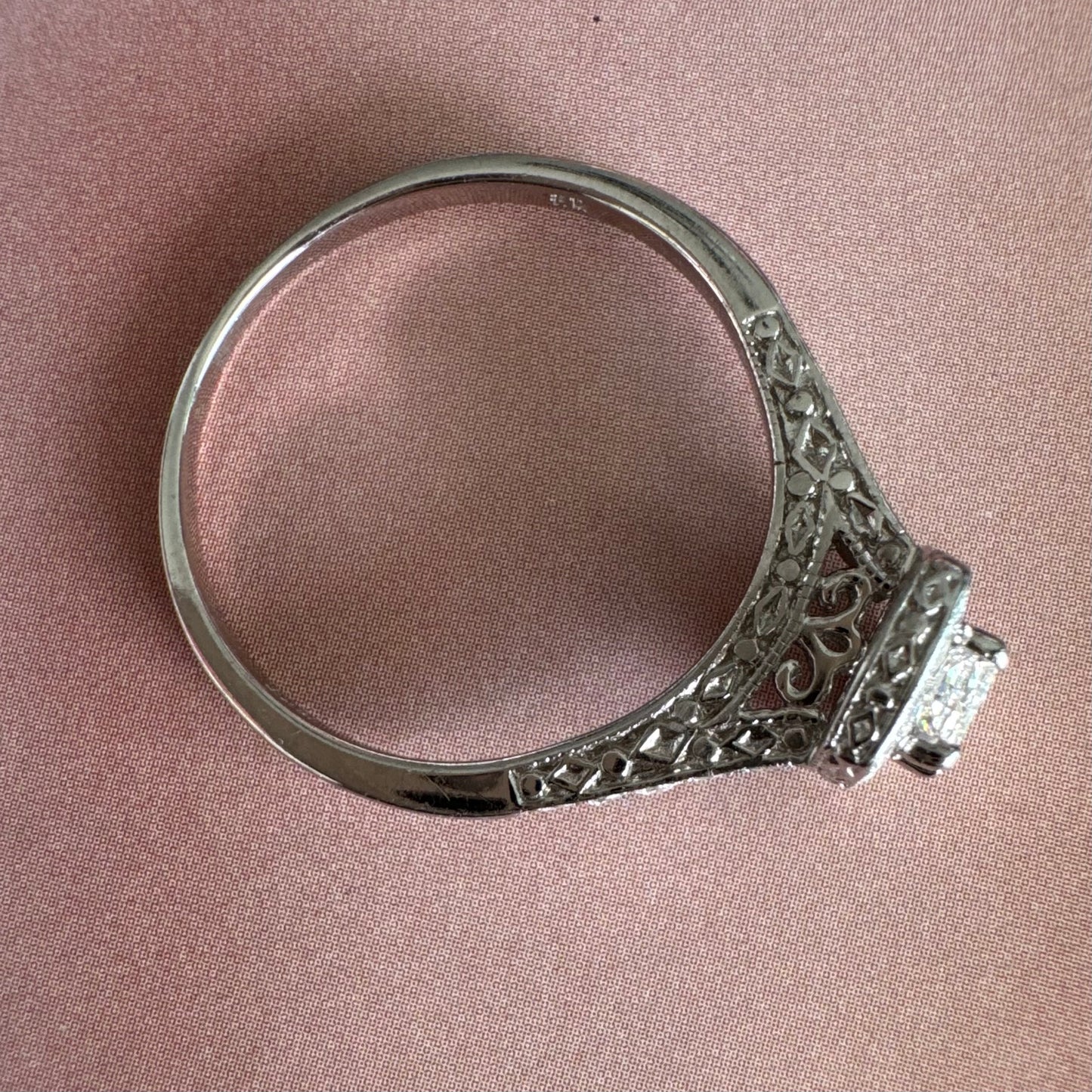 טבעת זהב לבן 14 קראט משובצת יהלום מרכזי בחיתוך פרינסס, מוקף הילת יהלומים קטנים וזרוע משובצת פאווה