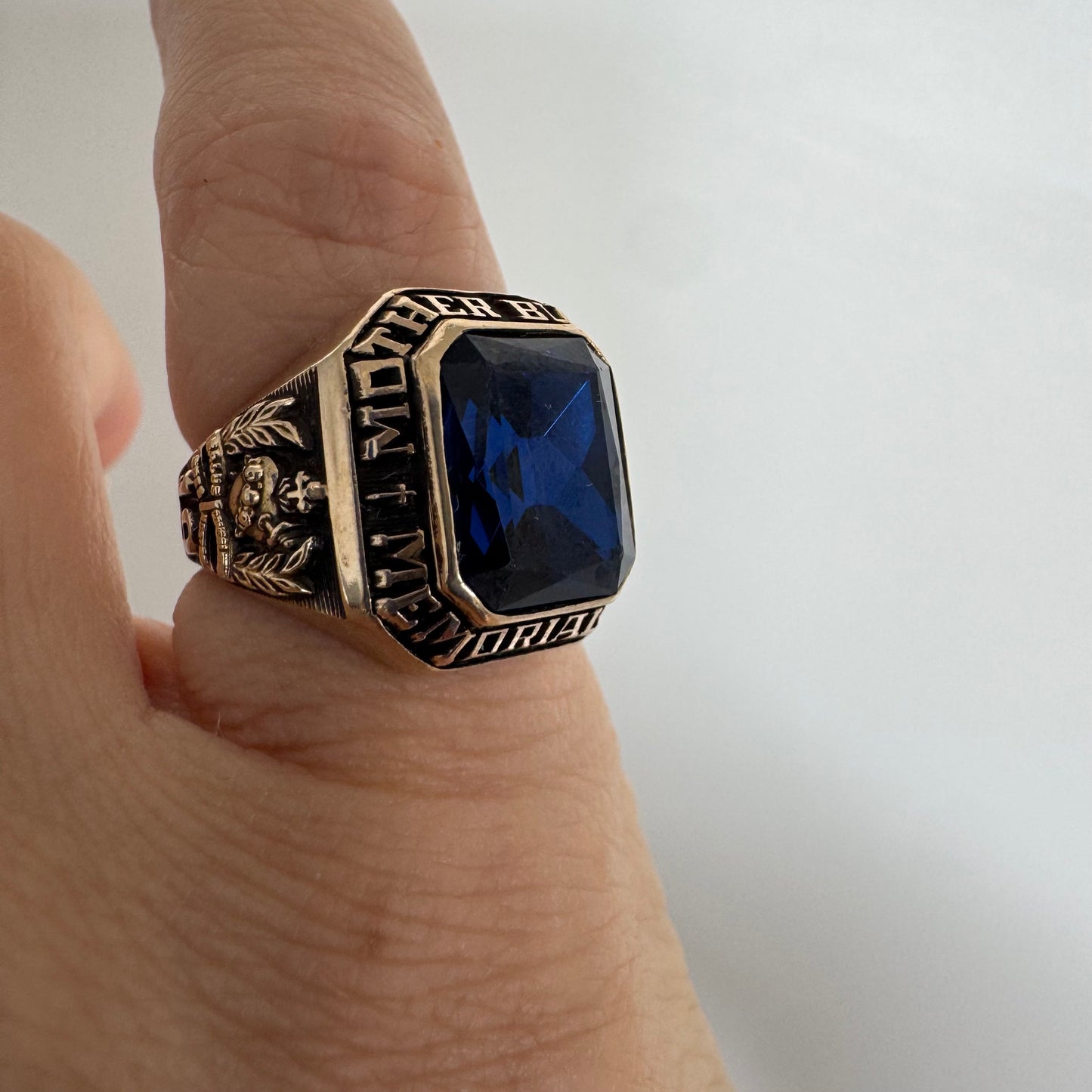 10K gold college ring set with a deep blue faceted stone.