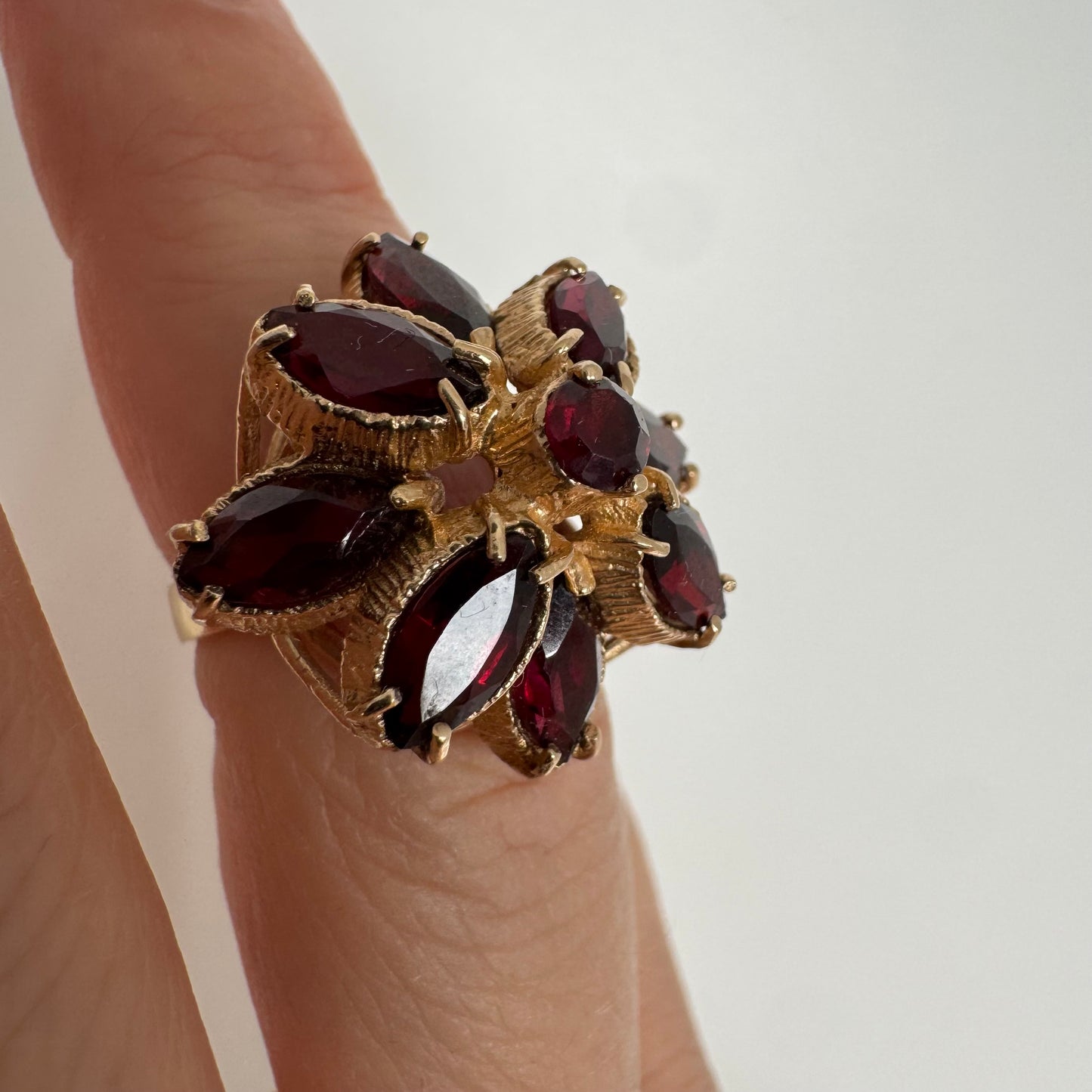 14K gold ring set with marquise-cut Garnets surrounding a round central stone.