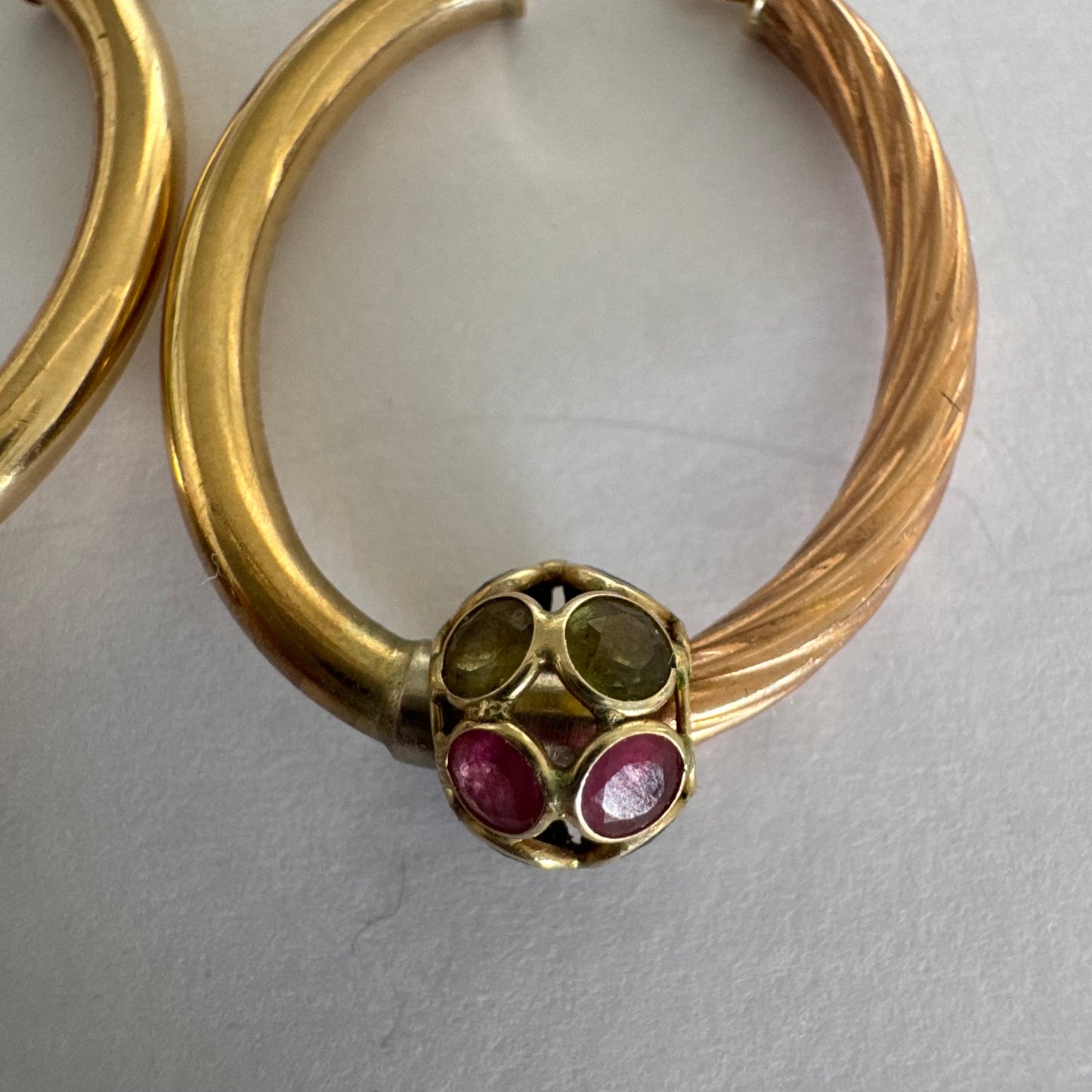 10K gold hoop earrings with a twisted design, set with pink and green Tourmaline.