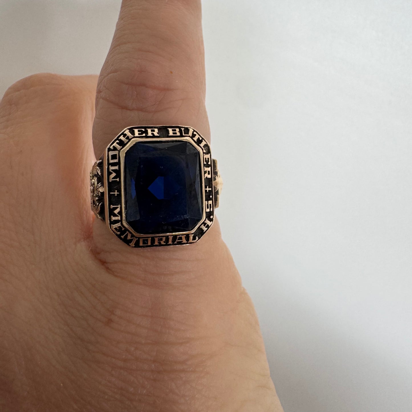 10K gold college ring set with a deep blue faceted stone.