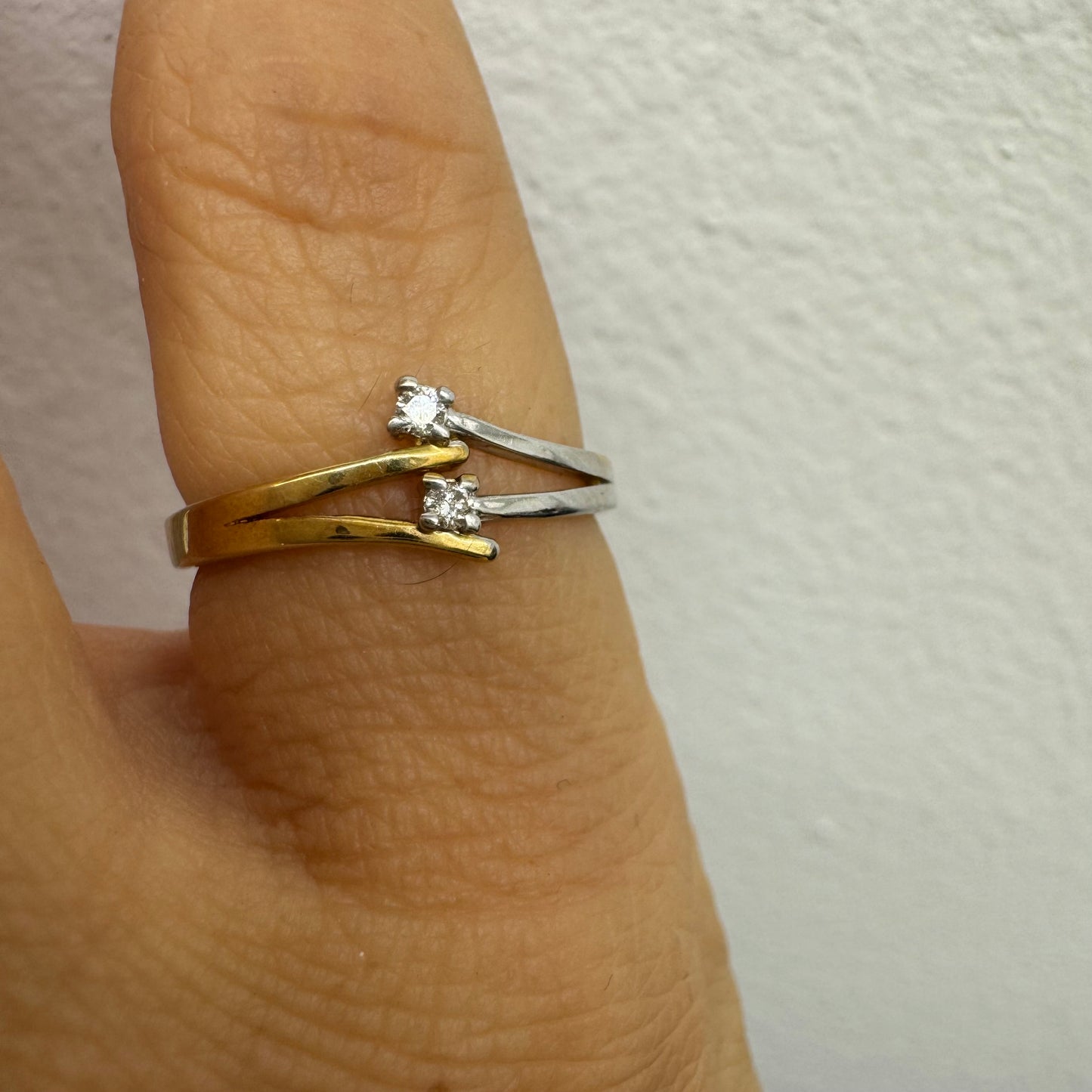טבעת זהב 14 קראט, עם זרועות מצטלבות בזהב צהוב וזהב לבן, שכל אחת מהן משובצת יהלום קטן ונוצץ.