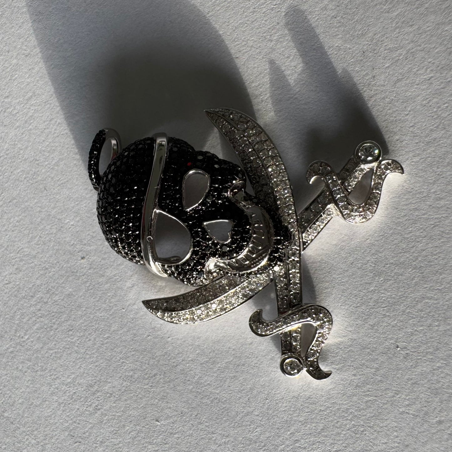 תליון זהב 14 קראט בצורת גולגולת/פיראט משובץ יהלומים לבנים ויהלומים שחורים בשיבוץ פאבה צפוף.