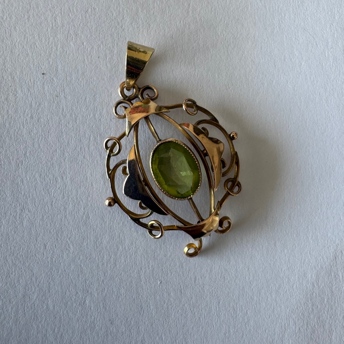 9K gold pendant featuring an oval-cut Peridot in a vibrant green hue.