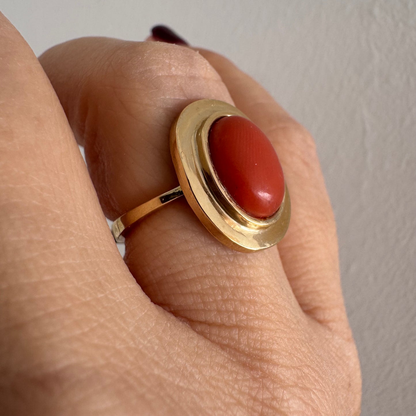 טבעת זהב 18 קראט משובצת אבן קורל אובלית בגימור קבושון, משובצת במסגרת חלקה ונקייה.