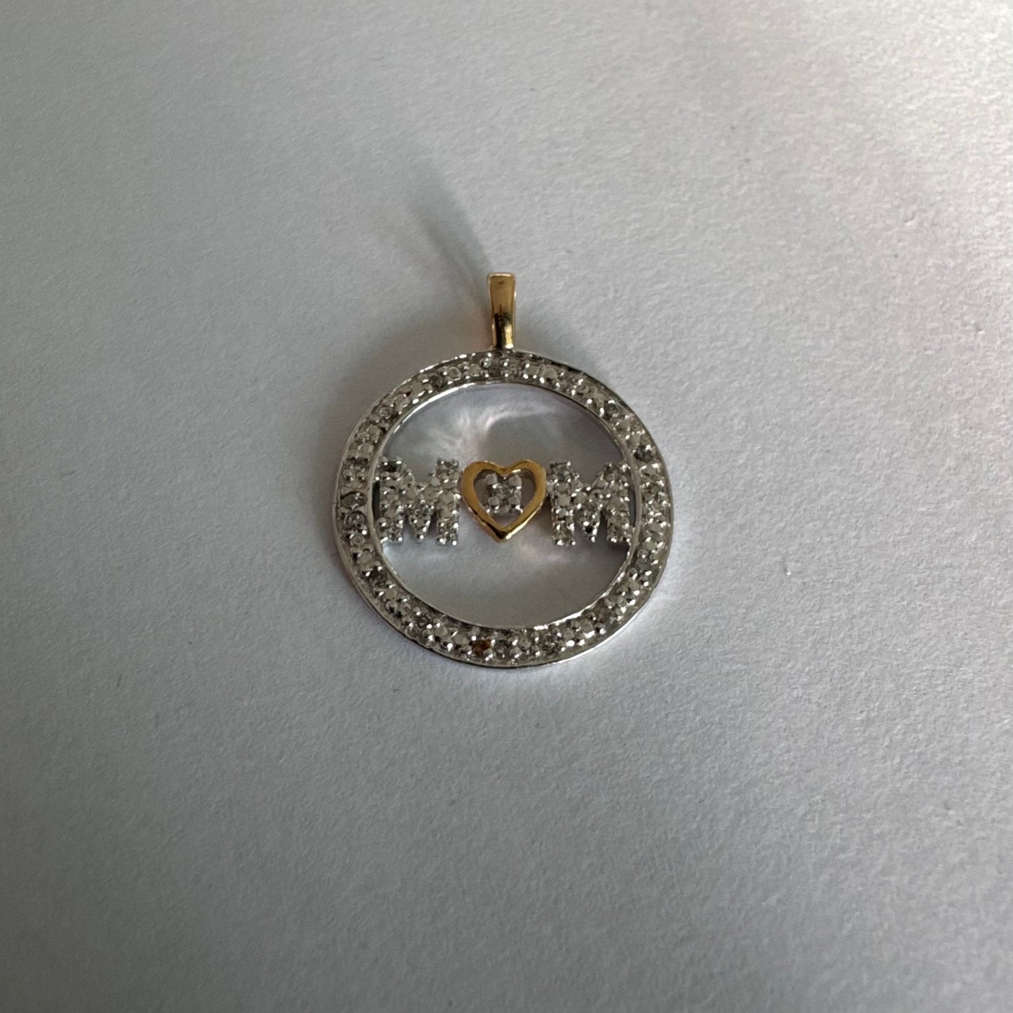 תליון זהב לבן 14 קראט עם הכיתוב ״MOM” מוקף מסגרת יהלומים עדינה.