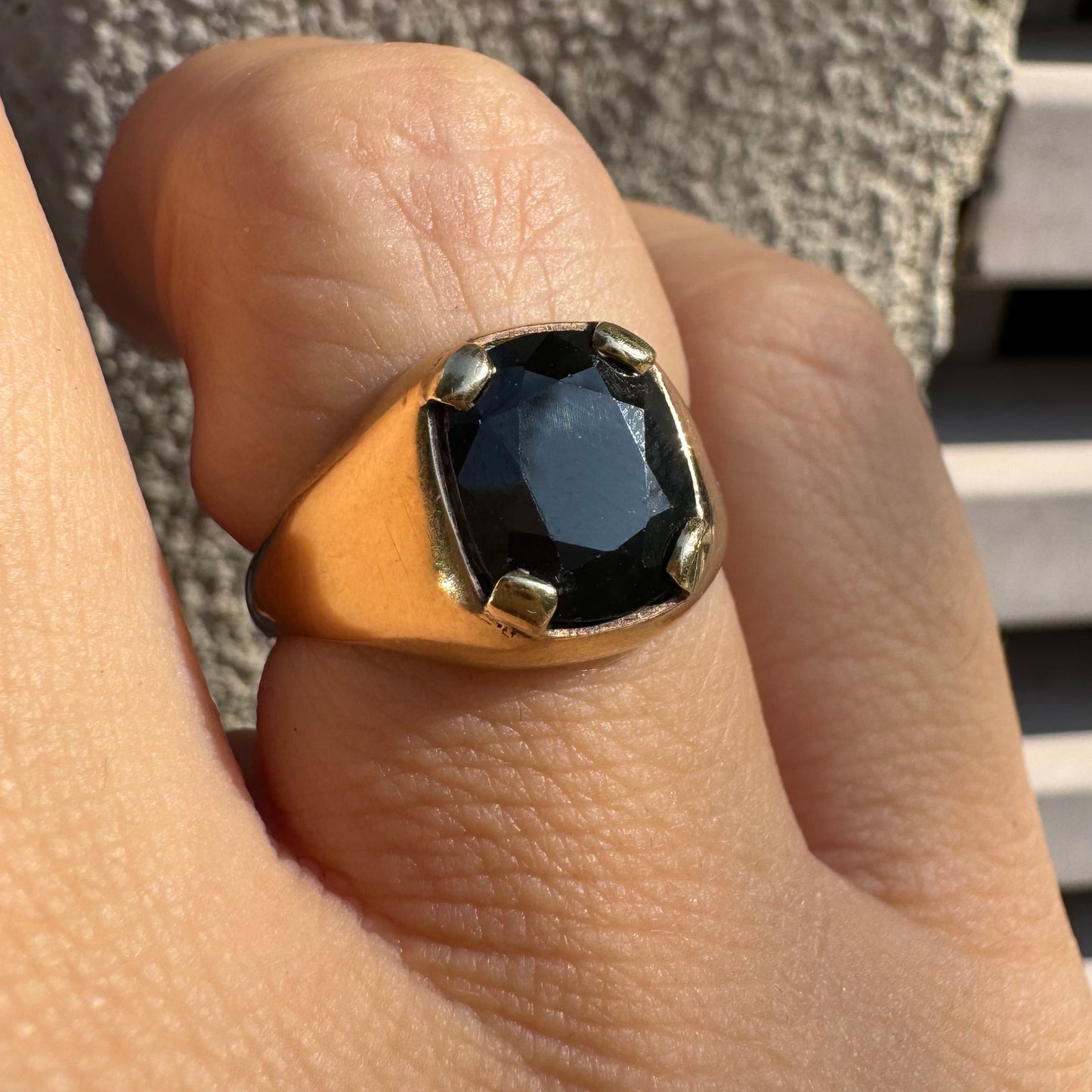 טבעת זהב 9 קראט משובצת ספיר ירוק כהה בחיתוך כרית ובתפסים עבים, בעיצוב נקי ובעל נוכחות. 