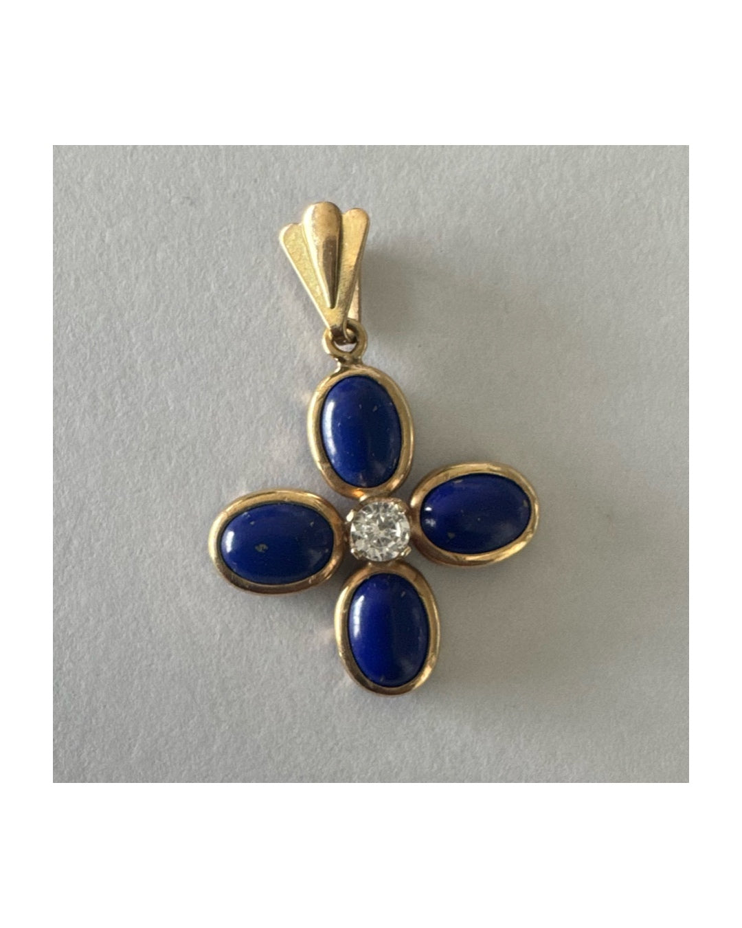 תליון זהב צהוב 14 קראט בעיצוב פרח סימטרי, משובץ ארבע אבני לפיס לזולי בגימור קבושון אובלי ובמרכזן יהלום עגול בוהק.