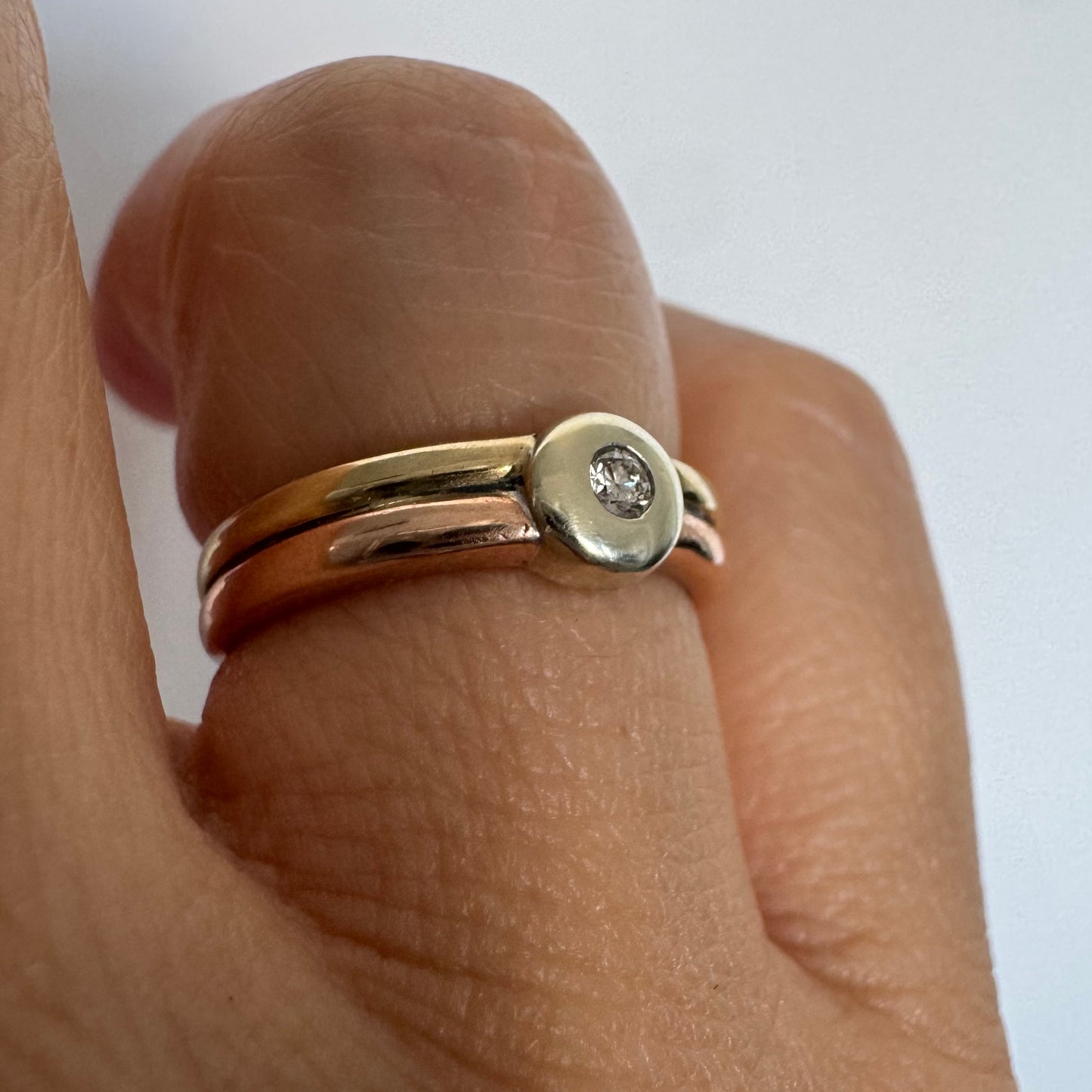 טבעת זהב 10 קראט בעיצוב מינימליסטי ונקי, משובצת יהלום מרכזי במסגרת חלקה (Bezel).