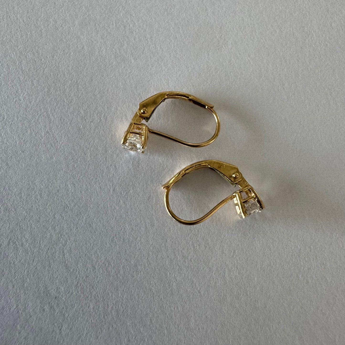 עגילי זהב 14 קראט משובצים יהלום עגול בשיבוץ קלאסי שמדגיש את האור והניקיון של האבן. 