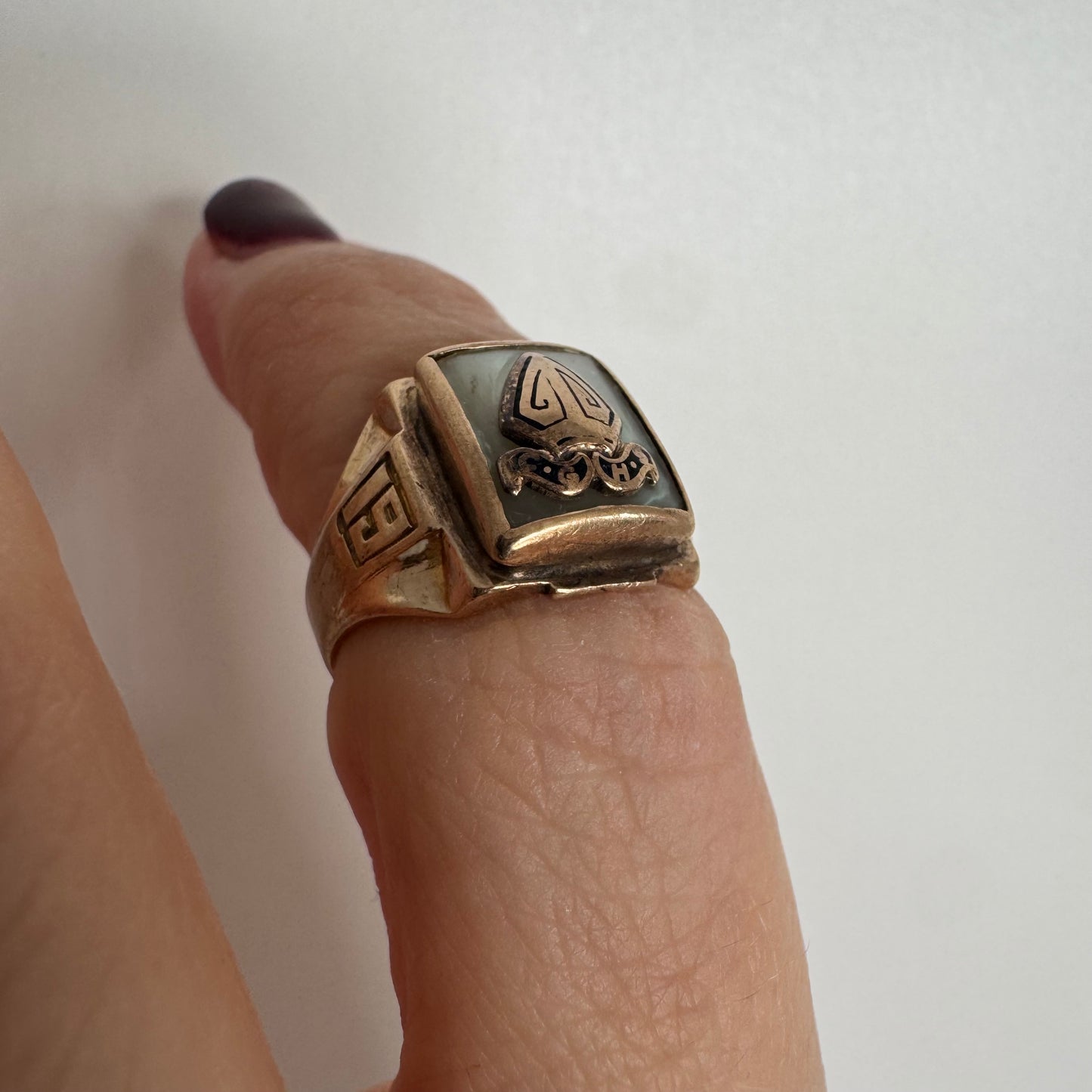 טבעת זהב 10 קראט בעיצוב חותם קלאסי, עם פלטה מרובעת משובצת לוח אם-הפנינה ועליה סמל פלר-דה-ליס מובלט.