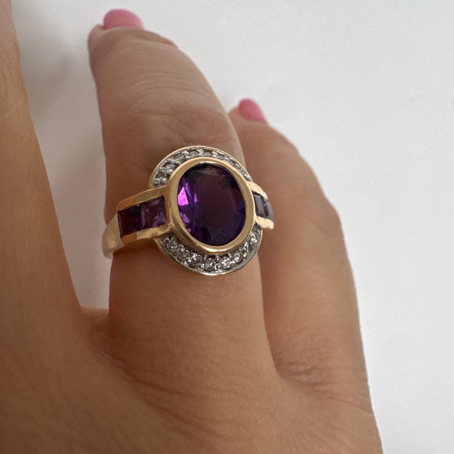 טבעת זהב 14 קראט בעיצוב ייחודי עם אבן אמטיסט אובלית מרכזית בגוון סגול עמוק, משובצת במסגרת חלקה ומודגשת ויהלומים.