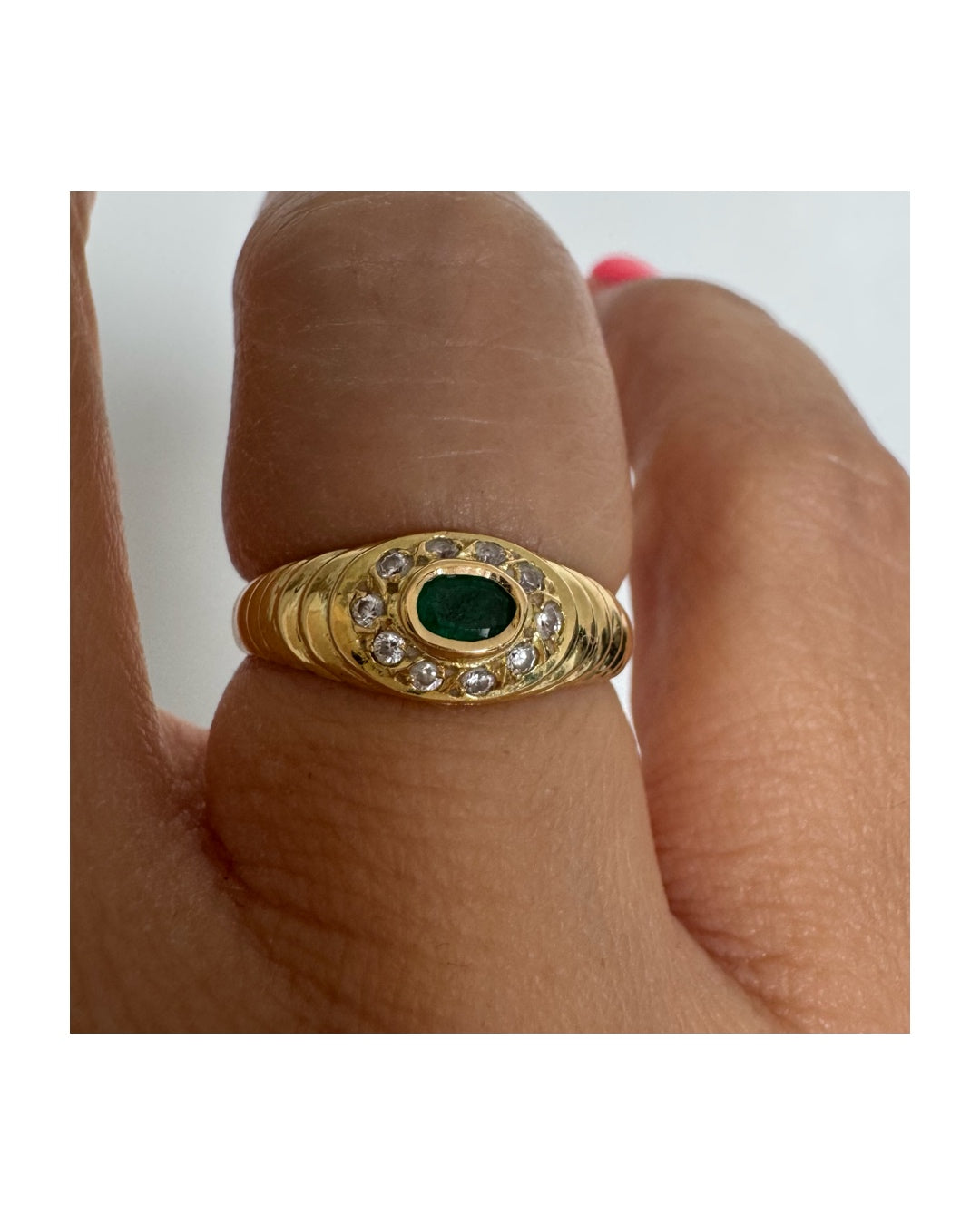 18K gold ring set with an oval Emerald at the center surrounded by Diamonds