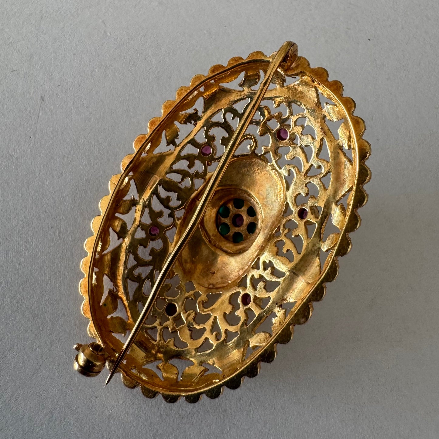 18K gold filigree brooch featuring intricate openwork detailing, accented with Ruby & Turquoise arranged in a floral centerpiece
