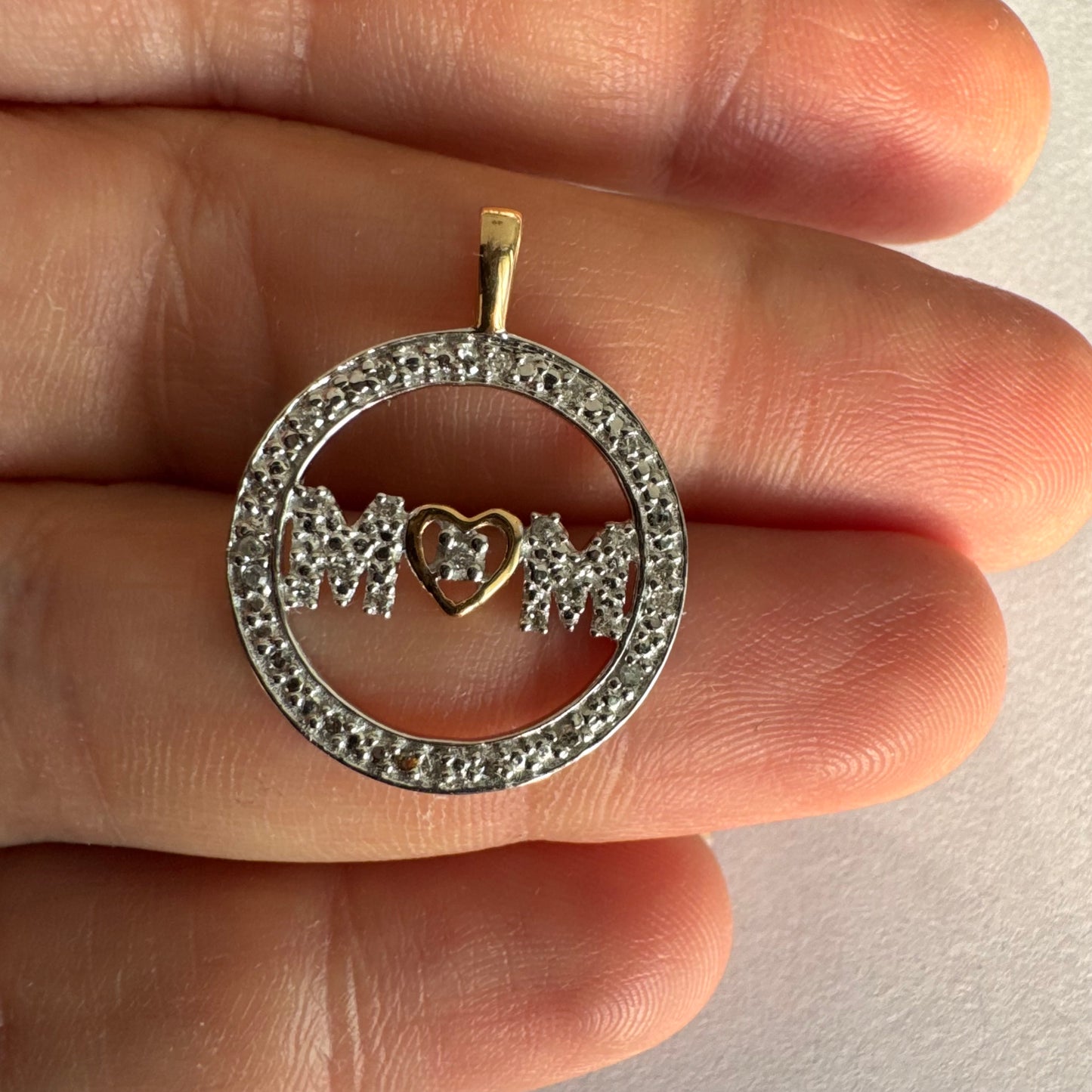 תליון זהב לבן 14 קראט עם הכיתוב ״MOM” מוקף מסגרת יהלומים עדינה.
