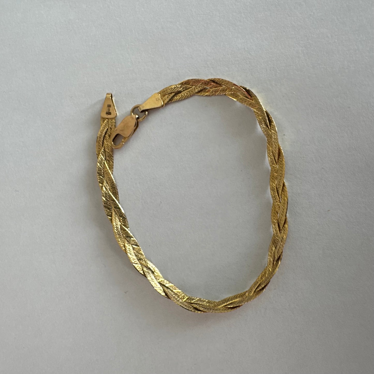 צמיד זהב צהוב 10 קראט בעיצוב קלוע עם טקסטורה עדינה שמחזירה אור וברק רך.