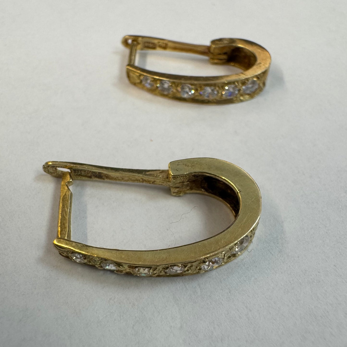 עגיל זהב צהוב 14 קראט בעיצוב אלגנטי ומודרני, משובץ שורת אבני חן שקופות שמעניקות ברק עדין ומדויק.