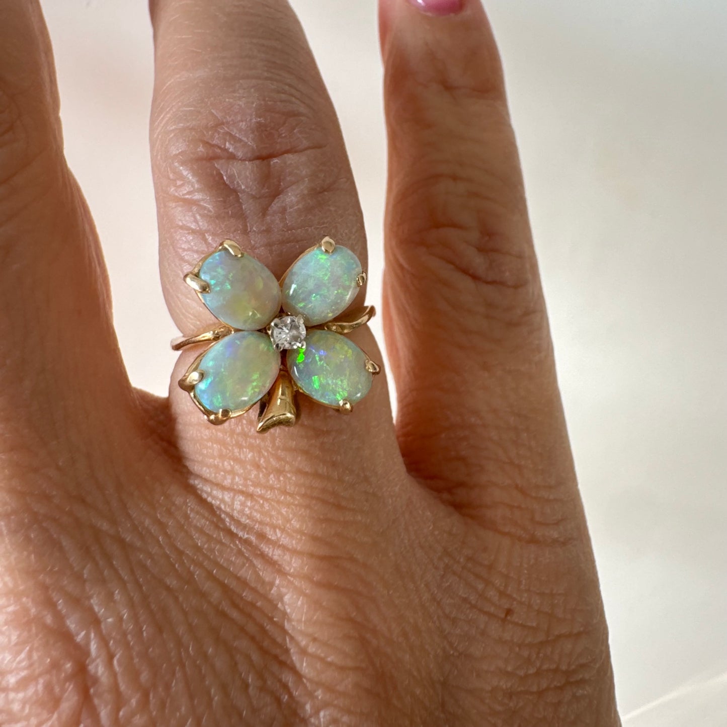 טבעת זהב 14 קראט בעיצוב פרח, משובצת ארבע אבני אופל בחיתוך טיפה ובמרכז יהלום טבעי.