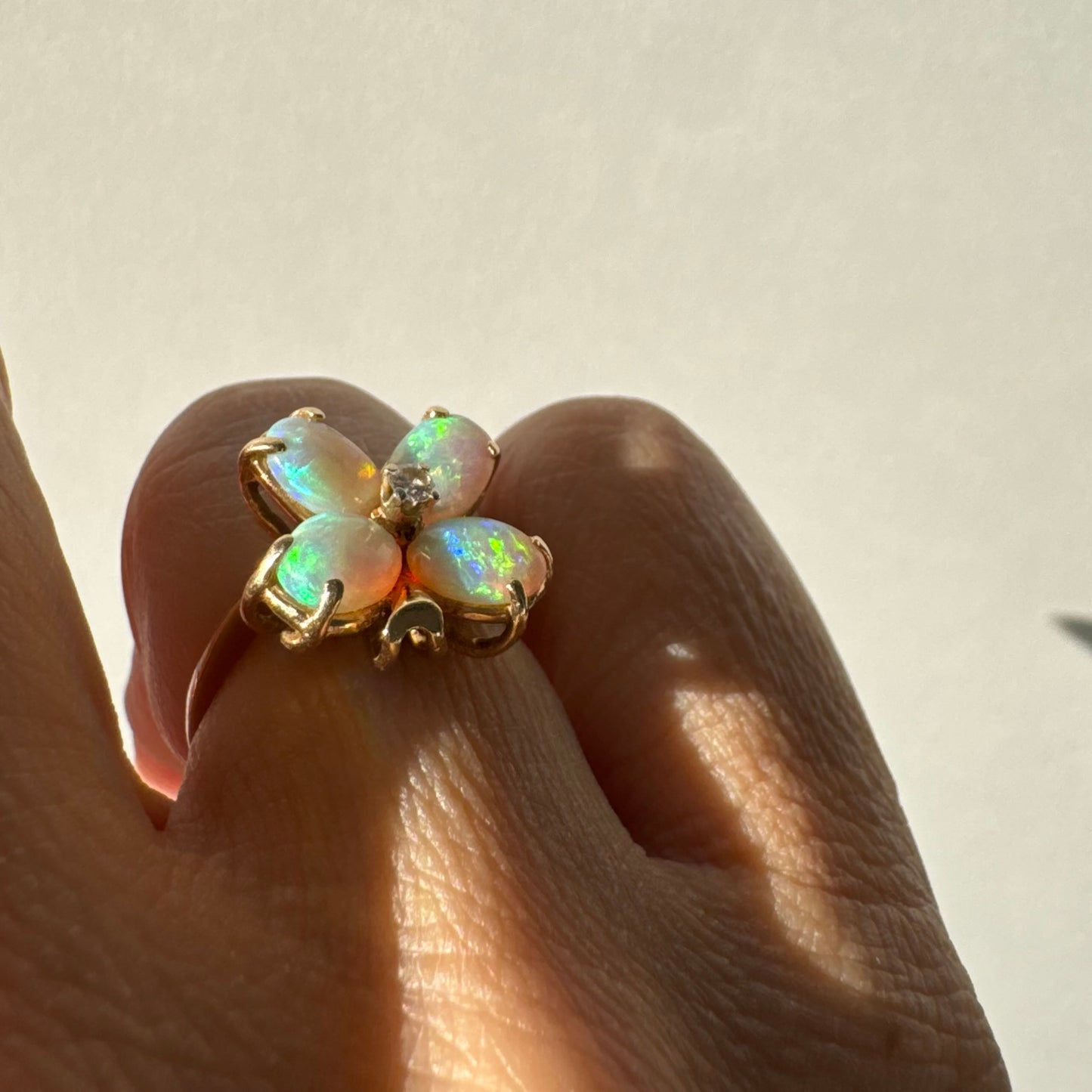 טבעת זהב 14 קראט בעיצוב פרח, משובצת ארבע אבני אופל בחיתוך טיפה ובמרכז יהלום טבעי.