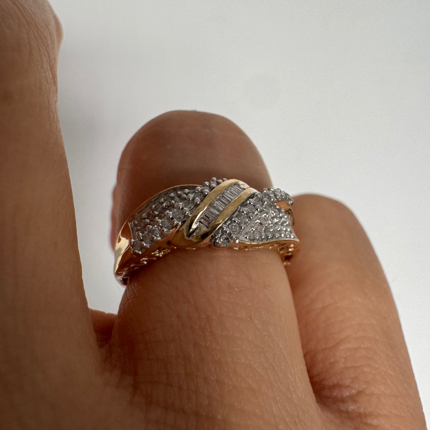 טבעת זהב 10 קראט משובצת יהלומים בחיתוך עגול לצד שורת יהלומי בגט במרכז.