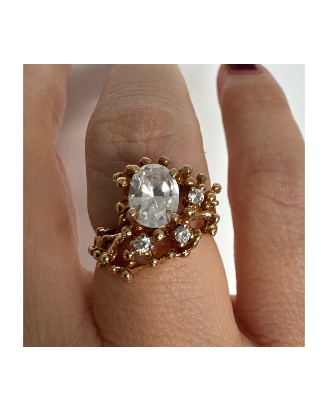 14K gold ring set with a central oval clear stone, accented by additional clear stones in an open, organic design.