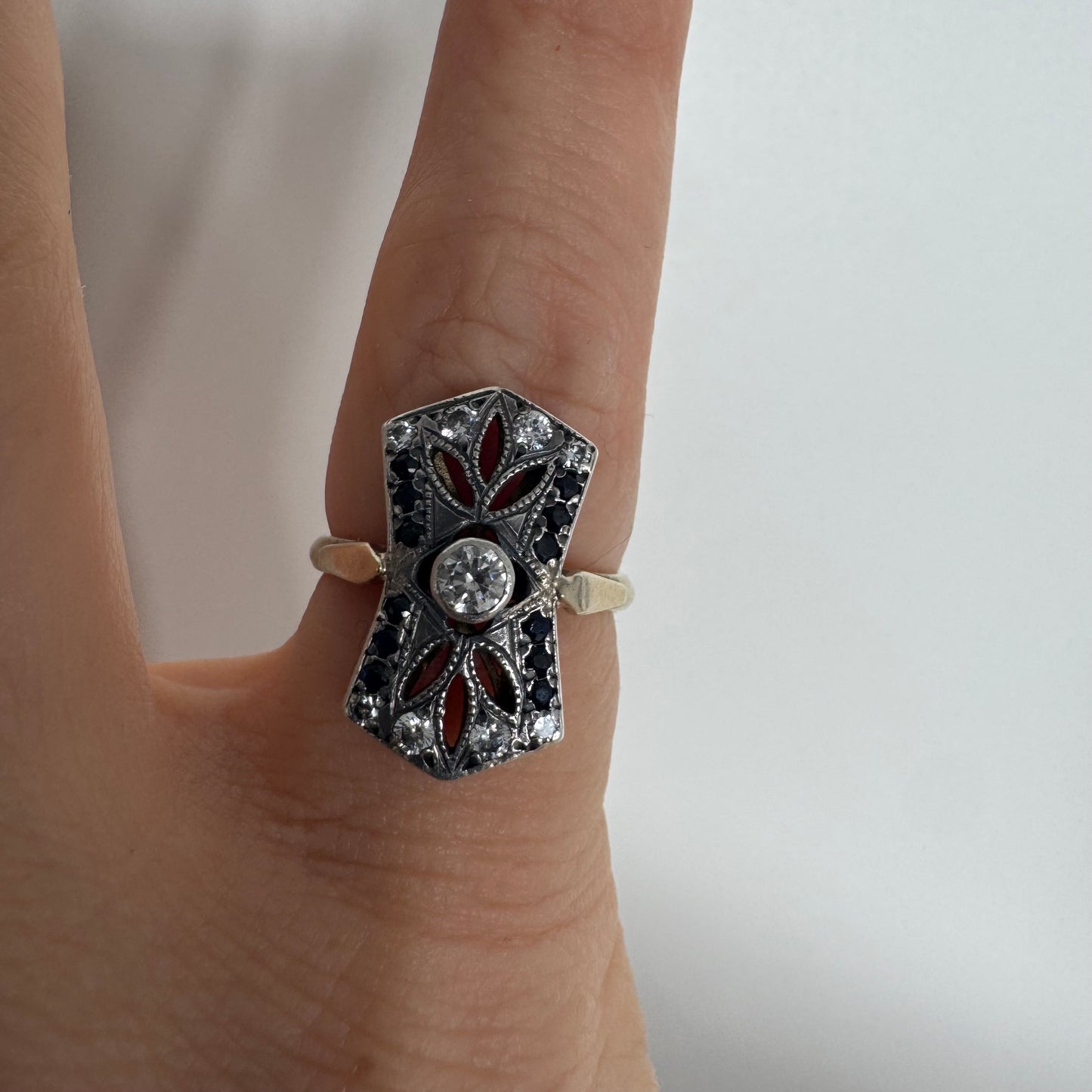 14K gold Art Deco ring set with a central Diamond, framed by deep blue Sapphires and accent Diamonds.