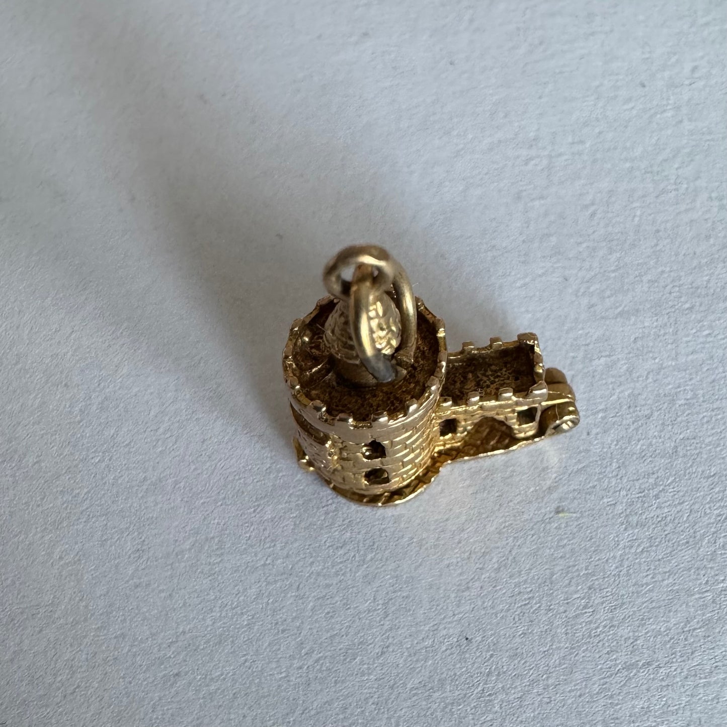 תליון זהב 9 קראט נדיר וייחודי, המהווה העתק פיסולי מפורט של ה-Bloody Tower (המגדל העקוב מדם) המפורסם ממצודת לונדון. התליון מעוצב בתלת-ממד (3D) עם טקסטורת לבנים מפורטת, צריחים, וחריטה של שם המגדל בגבו.