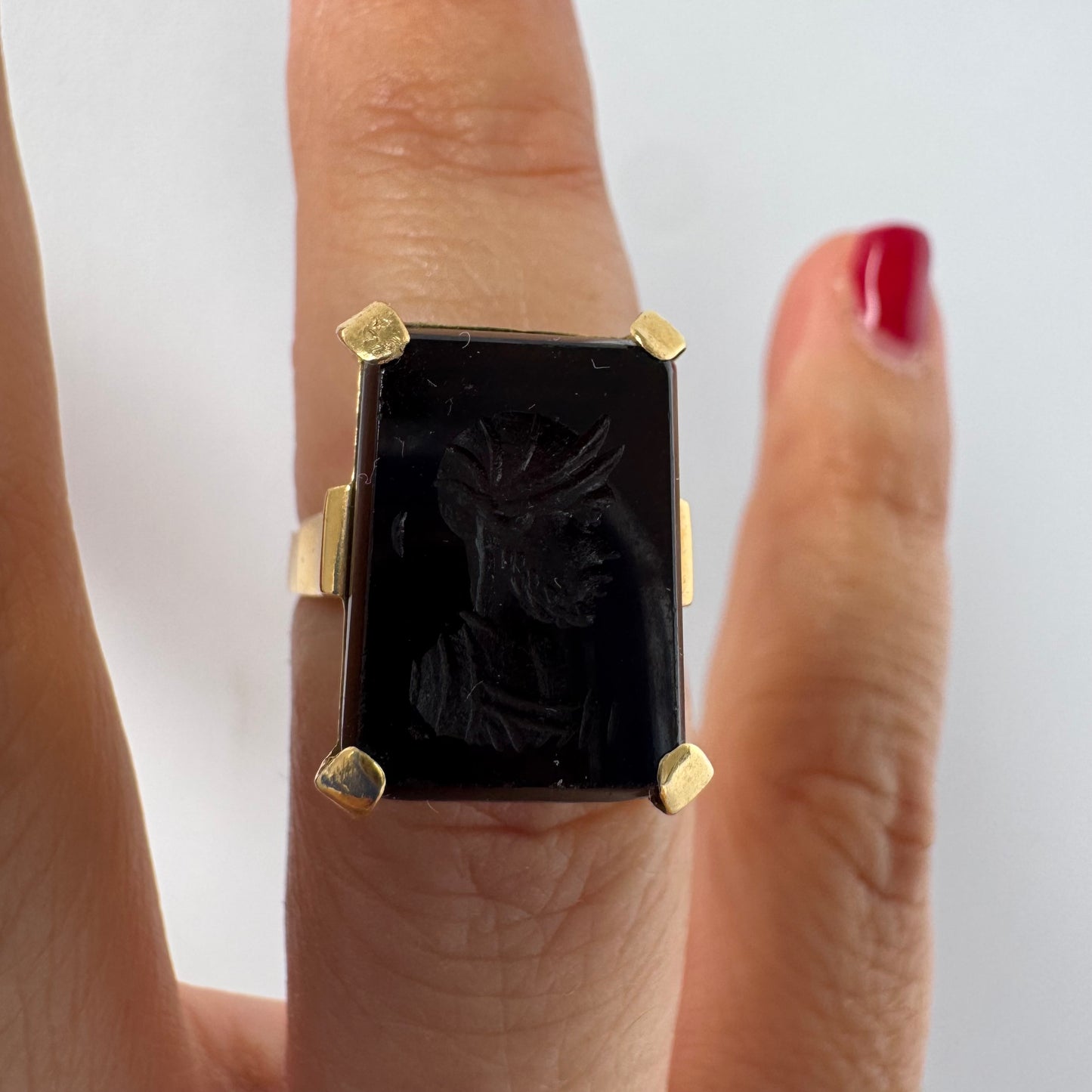 18K gold ring set with a carved dark stone featuring a classical warrior profile.