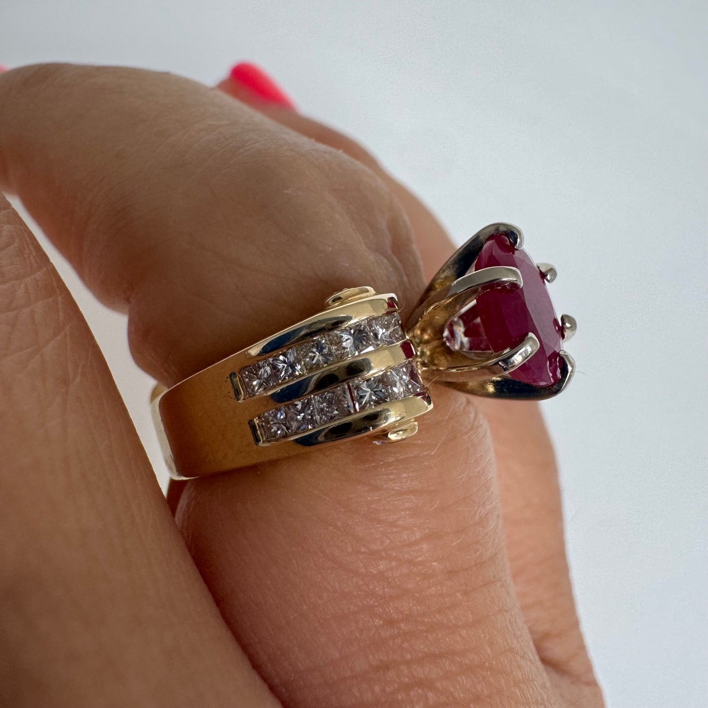14K gold ring set with a vivid natural Ruby at the center and accented by rows of Diamonds on both sides.