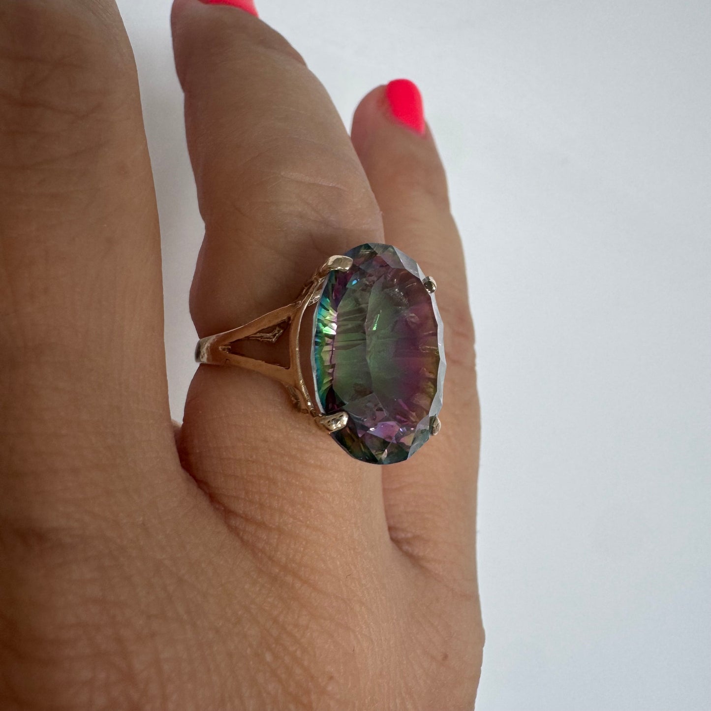 9K gold ring set with a large iridescent stone displaying mesmerizing shades of purple, green, and blue that shift beautifully in the light.