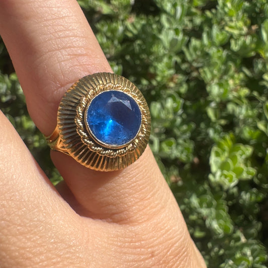 18K gold ring featuring a vibrant round Blue Topaz set in a textured gold bezel.