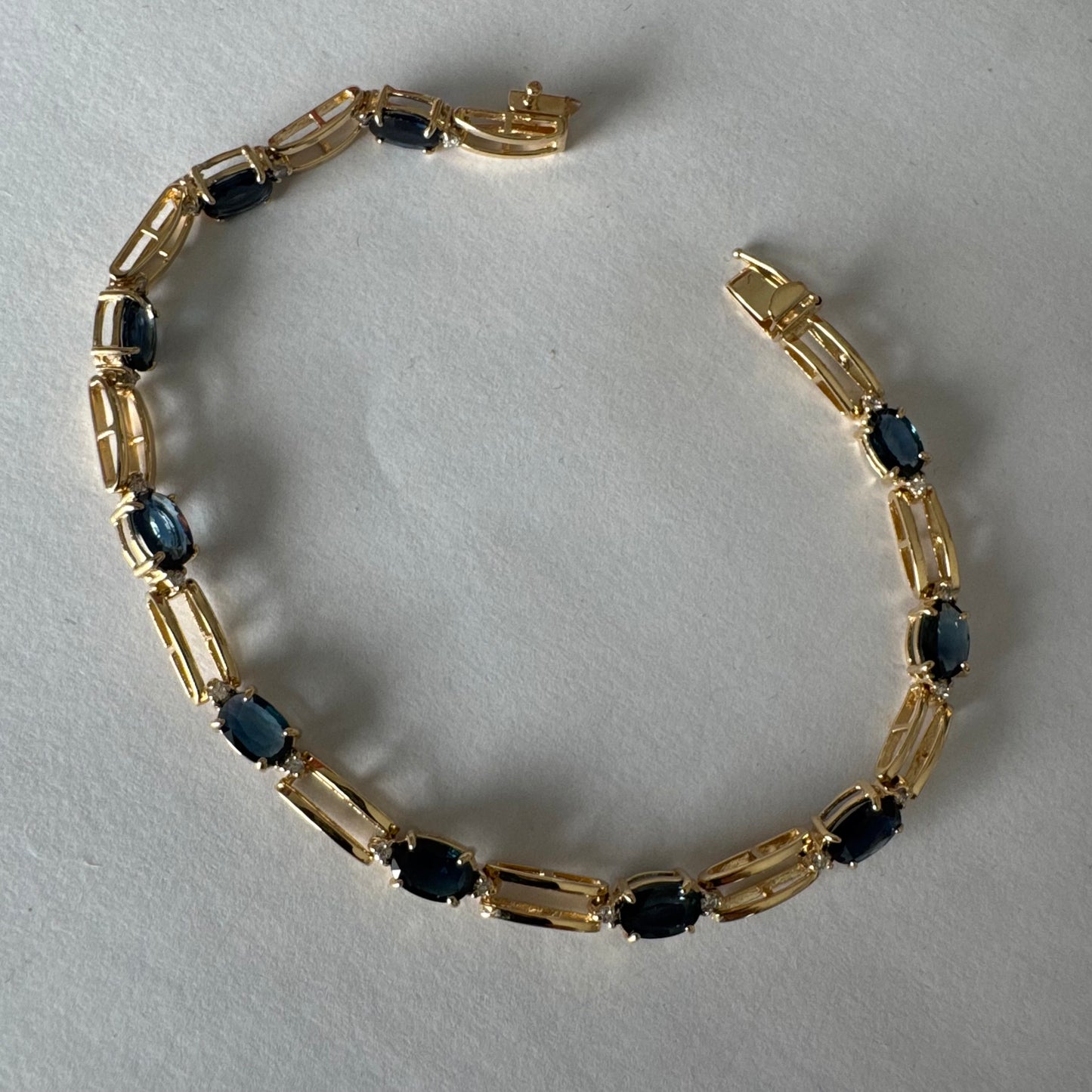 צמיד זהב צהוב 14 קראט משובץ אבני טופז כחולות בחיתוך אובלי, עם יהלומים המשובצים ביניהן להוספת ברק עדין.