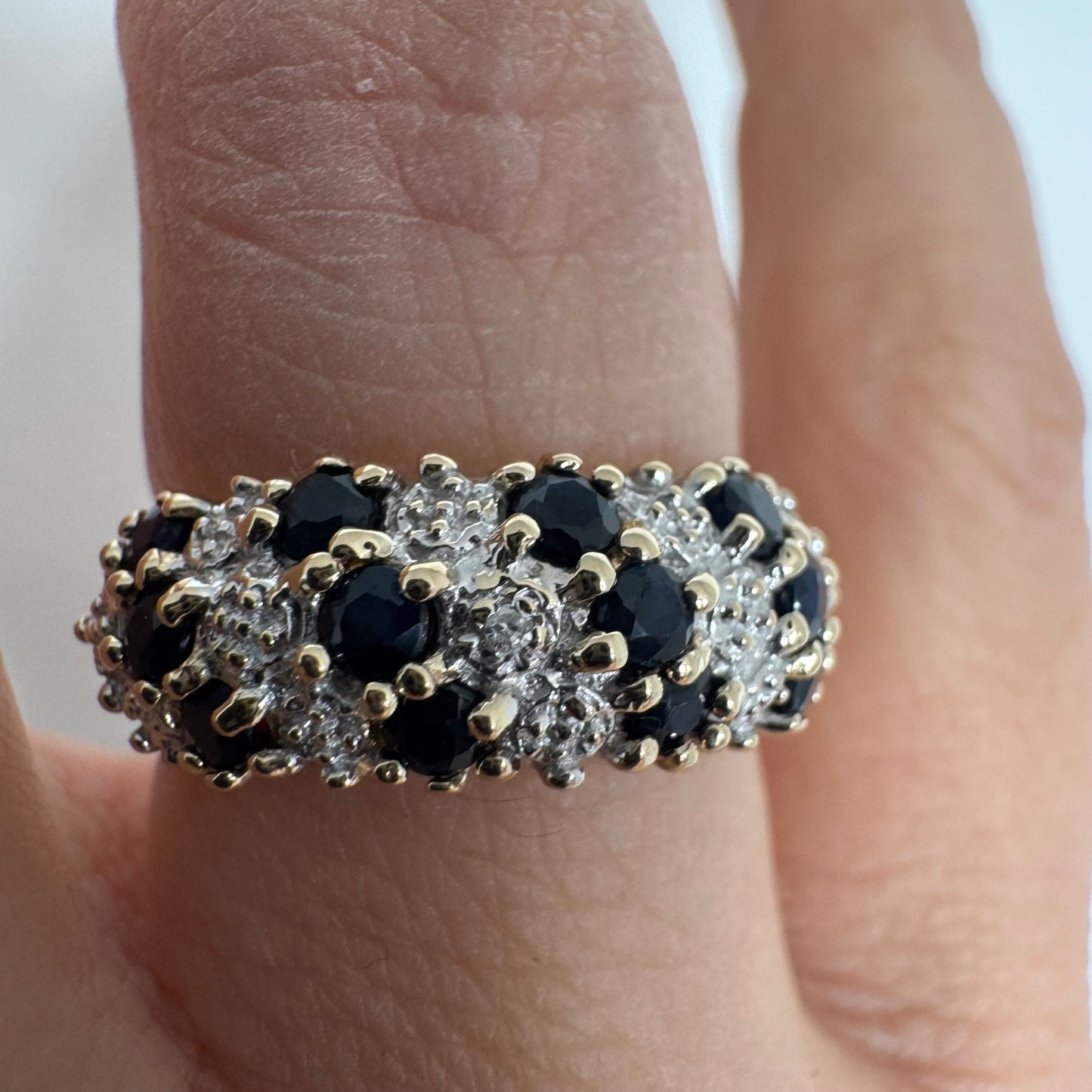 טבעת זהב צהוב 10 קראט משובצת אבני ספיר כהות ויהלומים בעיצוב קלאסי ורומנטי.