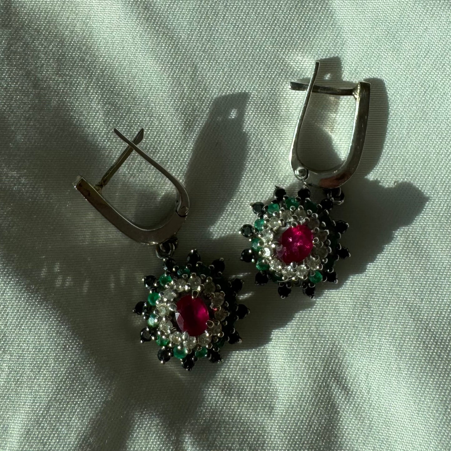 14K white gold drop earrings set with white and black Diamonds, Emeralds and a central Ruby