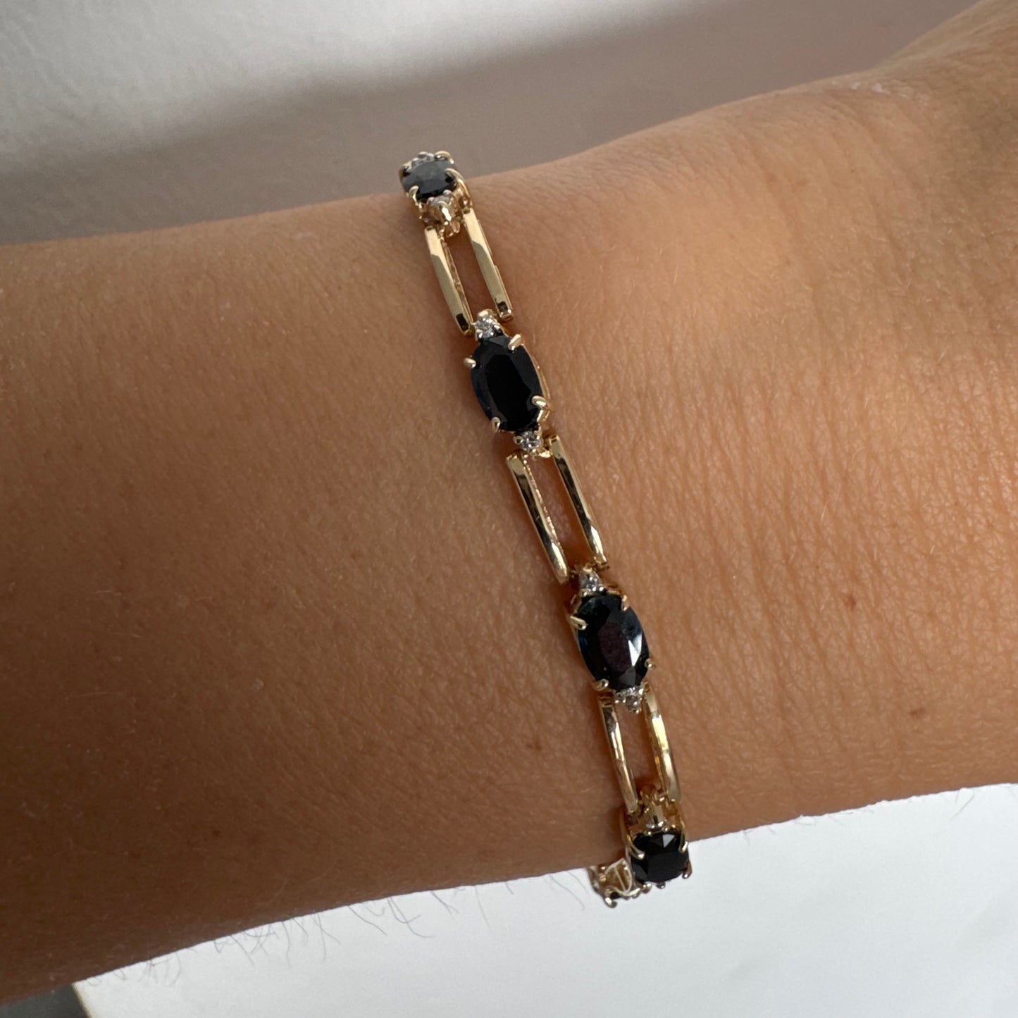 צמיד זהב צהוב 14 קראט משובץ אבני טופז כחולות בחיתוך אובלי, עם יהלומים המשובצים ביניהן להוספת ברק עדין.