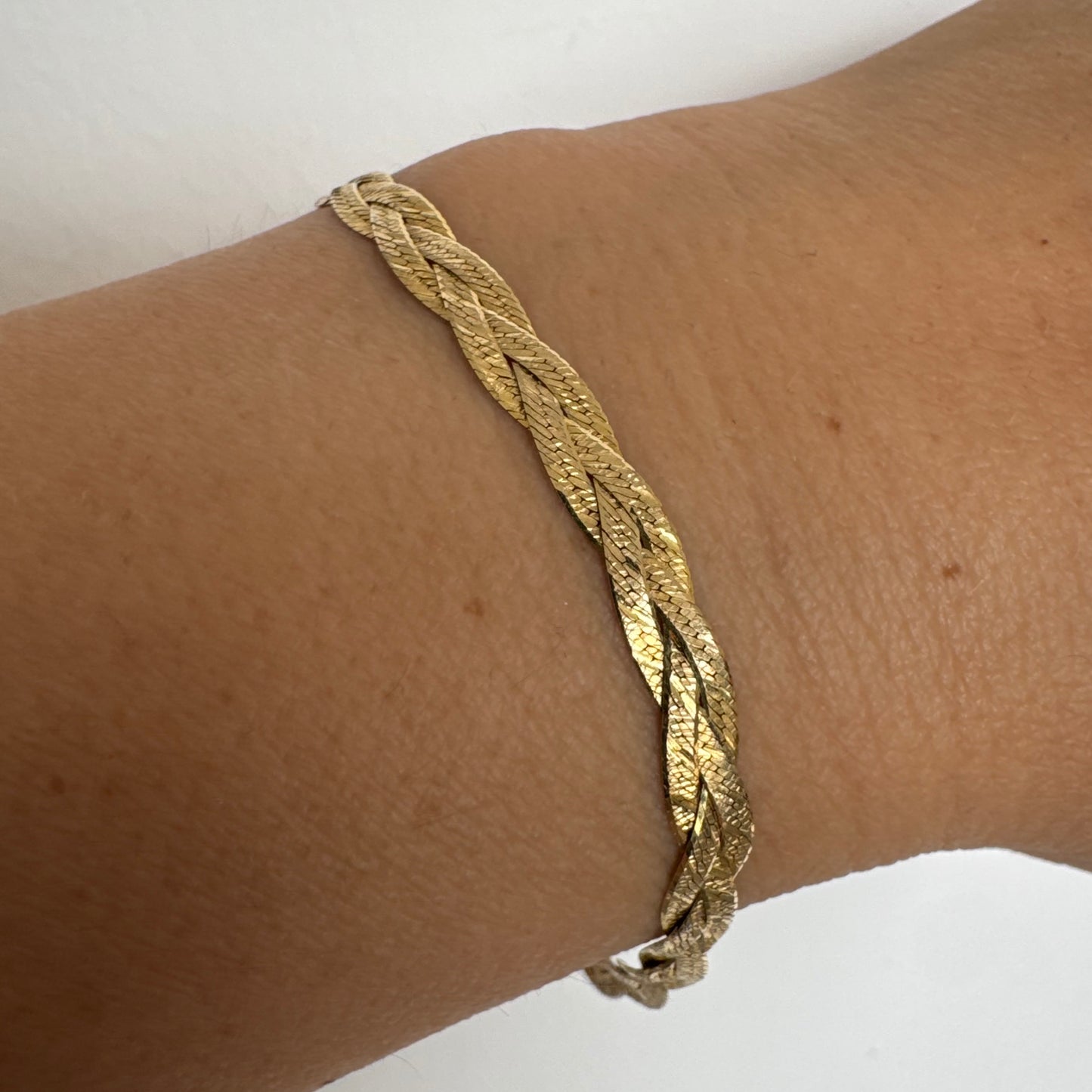 צמיד זהב צהוב 10 קראט בעיצוב קלוע עם טקסטורה עדינה שמחזירה אור וברק רך.