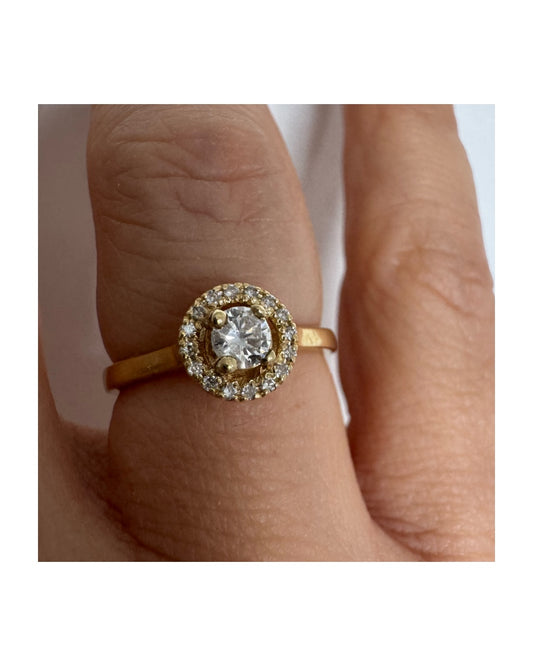 טבעת זהב צהוב 14 קראט משובצת יהלום מרכזי עגול, המוקף בהילה (Halo) של יהלומים מנצנצים.