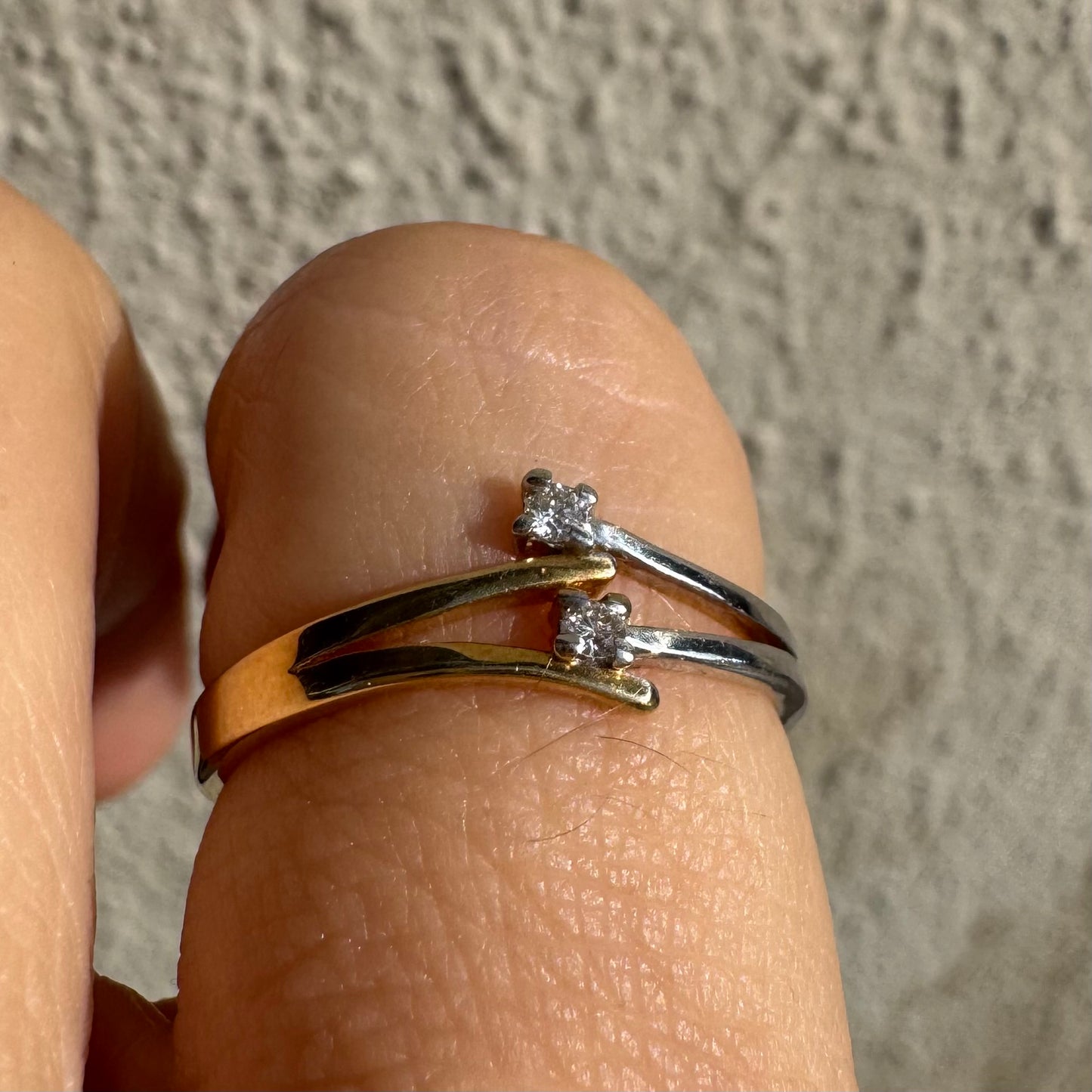 טבעת זהב 14 קראט, עם זרועות מצטלבות בזהב צהוב וזהב לבן, שכל אחת מהן משובצת יהלום קטן ונוצץ.