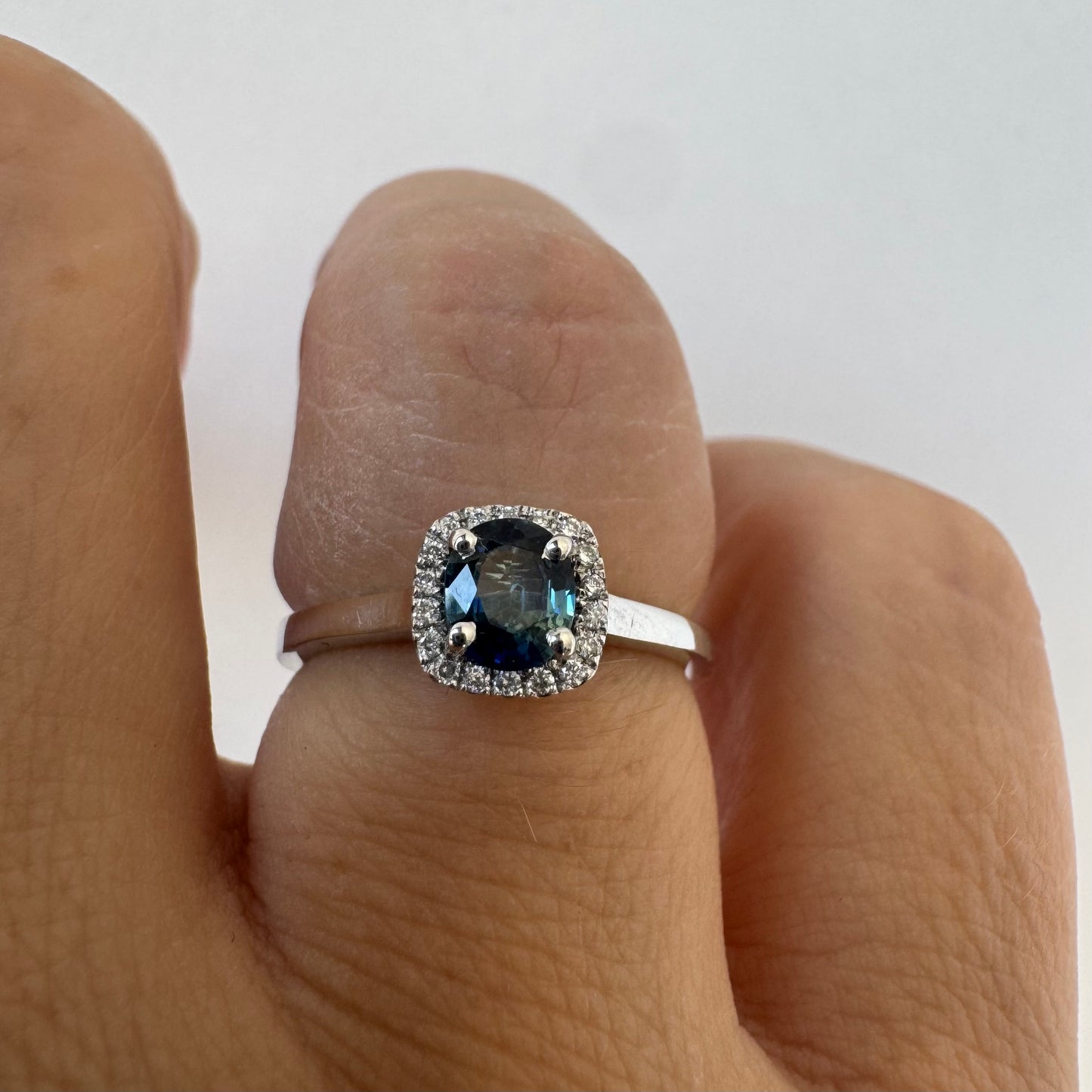 14K gold ring set with an oval blue Sapphire at the center framed by a delicate halo of sparkling Diamonds.
