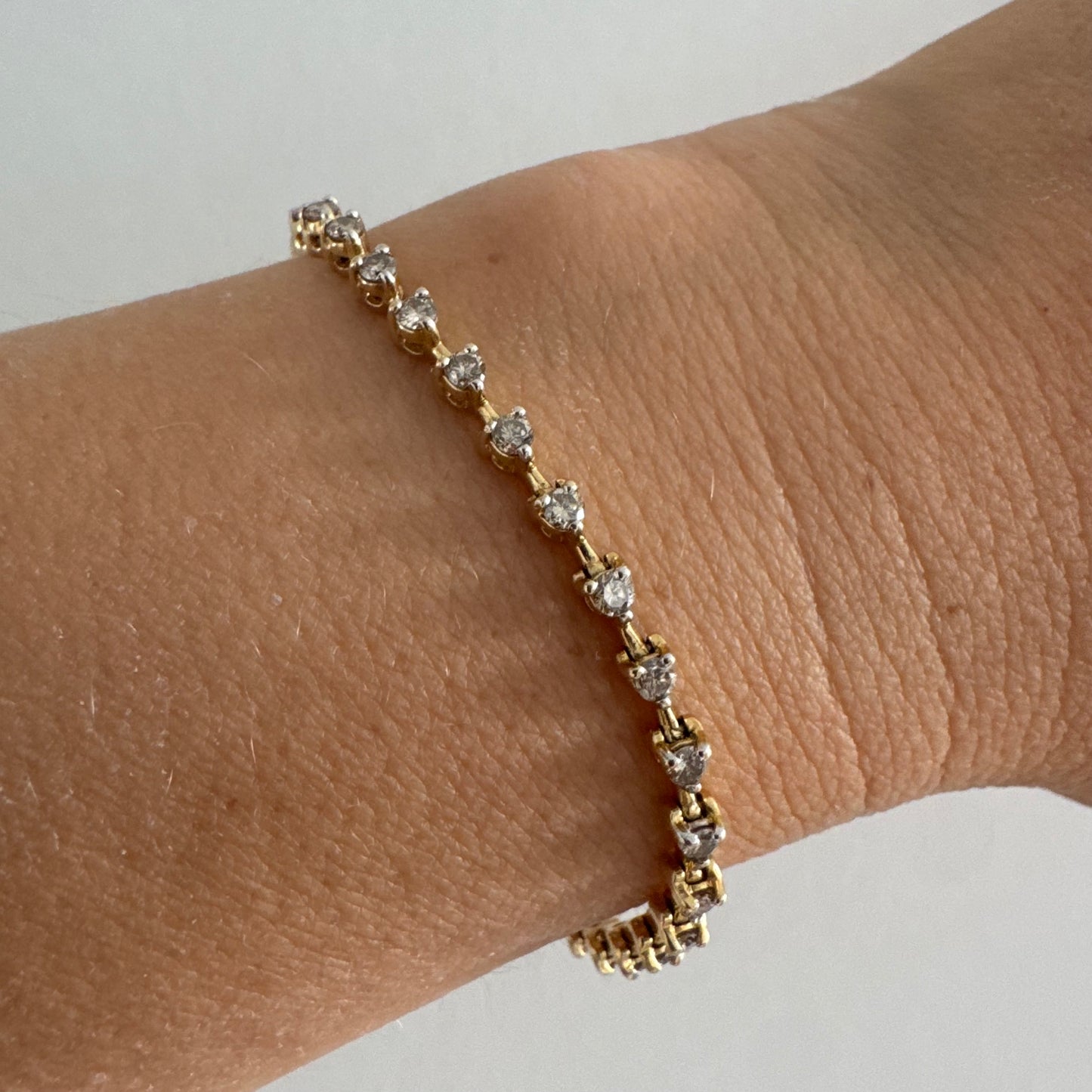 צמיד טניס מזהב צהוב 14 קראט משובץ שורת יהלומים, היוצרים ברק רציף ומראה נקי ועל-זמני.