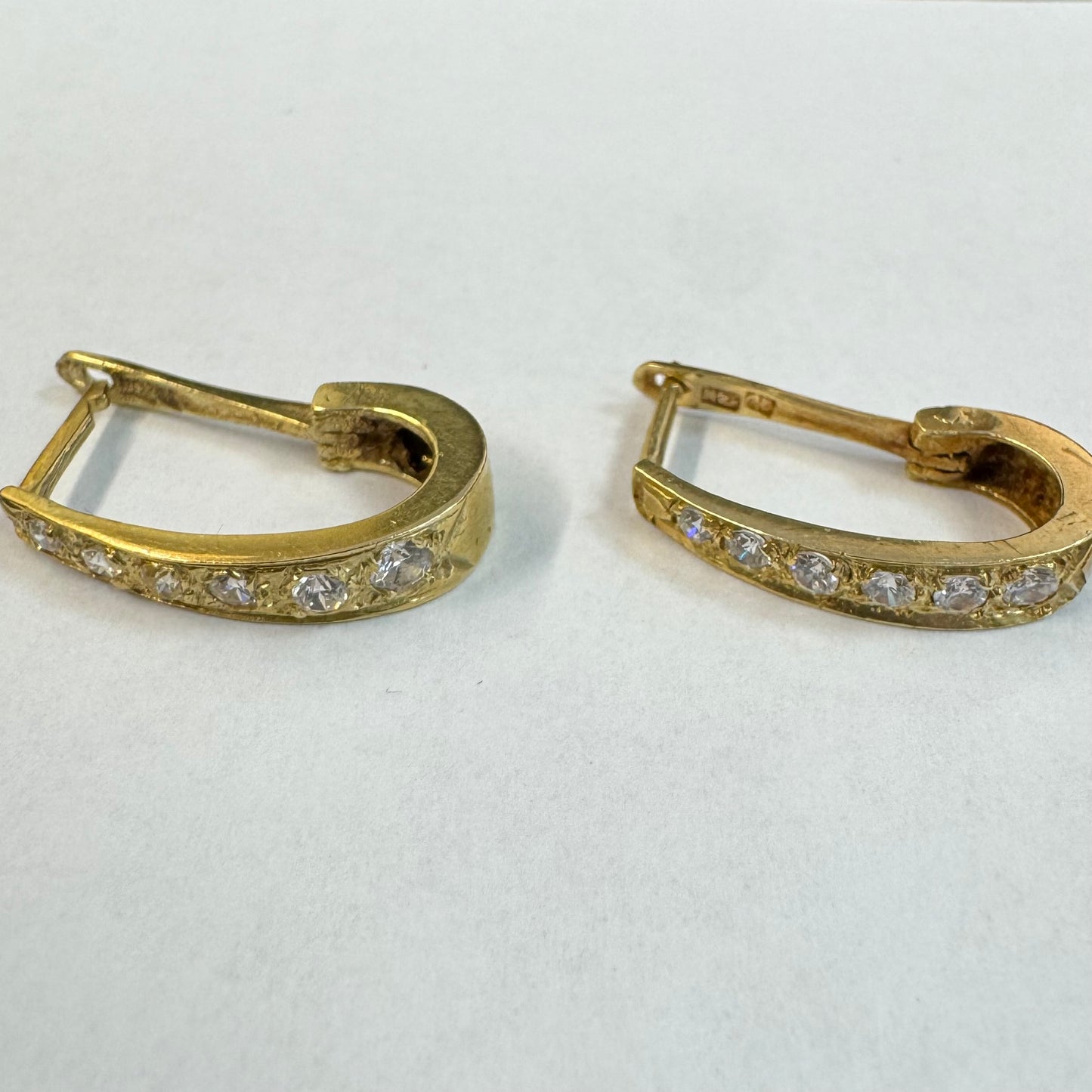 עגיל זהב צהוב 14 קראט בעיצוב אלגנטי ומודרני, משובץ שורת אבני חן שקופות שמעניקות ברק עדין ומדויק.