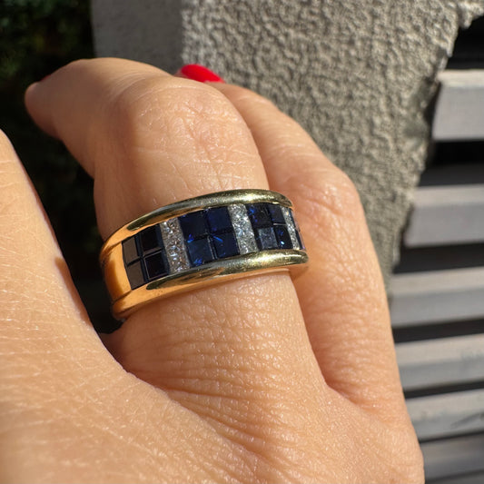 טבעת ה.שטרן זהב צהוב 18 קראט, בעיצוב רחב ומרשים. משובצת שורת אבני ספיר כחולות מרובעות בשילוב מחיצות של יהלומים לנגיעת ברק יוקרתי.