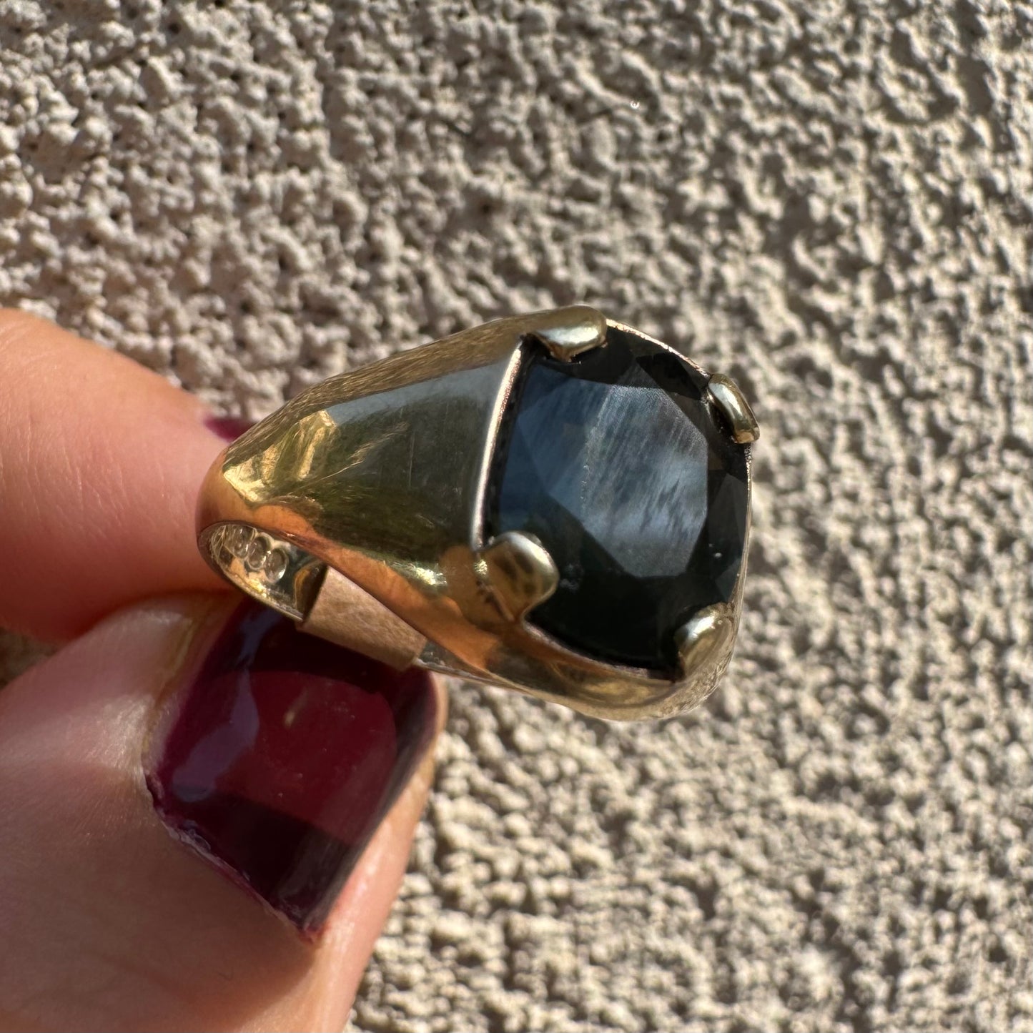 טבעת זהב 9 קראט משובצת ספיר ירוק כהה בחיתוך כרית ובתפסים עבים, בעיצוב נקי ובעל נוכחות. 