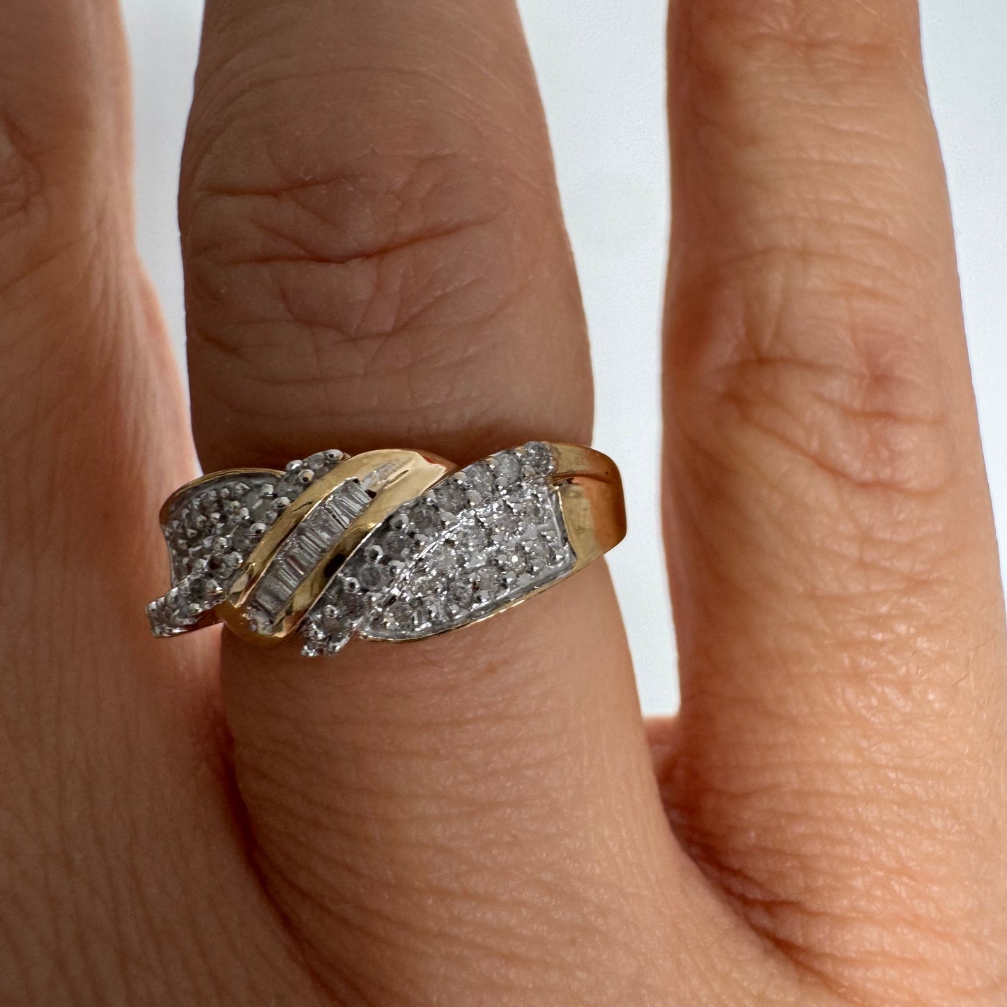 טבעת זהב 10 קראט משובצת יהלומים בחיתוך עגול לצד שורת יהלומי בגט במרכז.