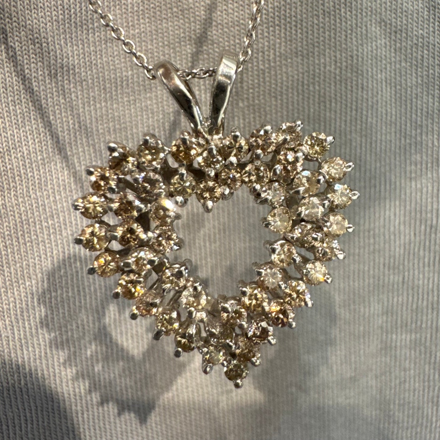 תליון לב זהב לבן 14 קראט, משובץ יהלומים בשיבוץ שיניים עדין היוצר מראה עשיר ומלא ברק.