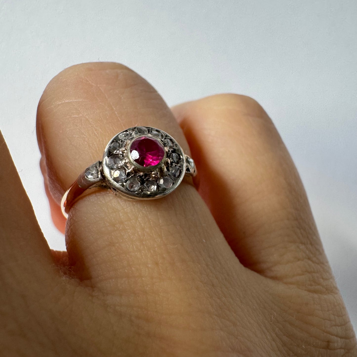 18K gold ring set with a round Ruby at the center, surrounded by a halo of old-cut Diamonds.
