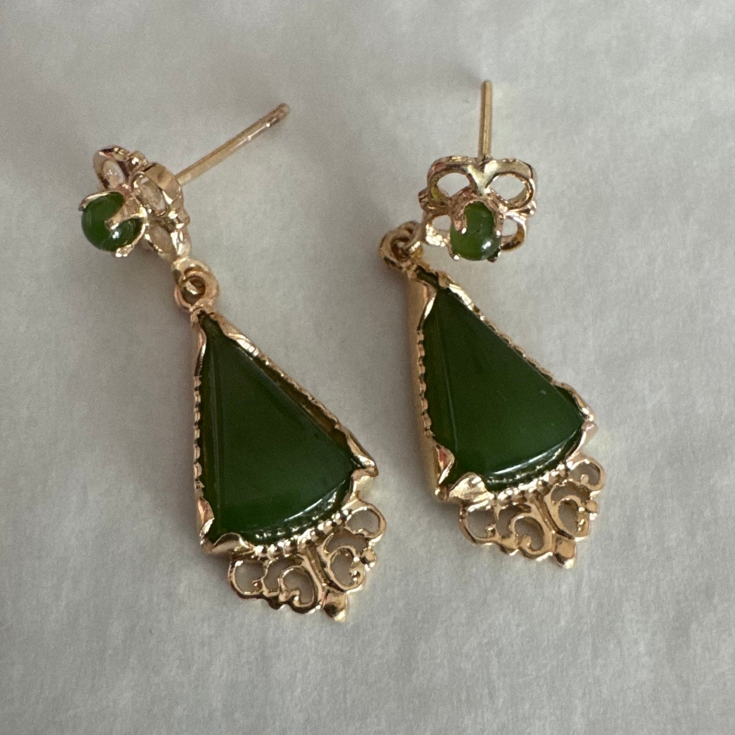 עגילי זהב צהוב 14 קראט משובצים אבני ג׳ייד ירוקות בגוון עמוק בחיתוך משולש.